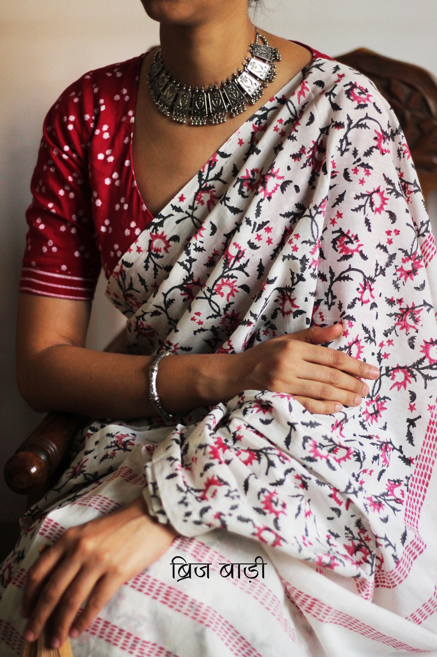 Off-white soft cotton saree by Brij Bari, hand block printed by skilled artisans with a striking floral pattern in pink and black for a fresh, elegant appeal. The saree is light-weight and breathableāideal for summer wear and everyday comfort. The pallu is detailed with handcrafted light green thread tassels, adding a subtle yet artistic finishing touch. Comes with a free hand block printed blouse piece that complements the sareeās colour palette. A versatile, handcrafted piece perfect for daily wear