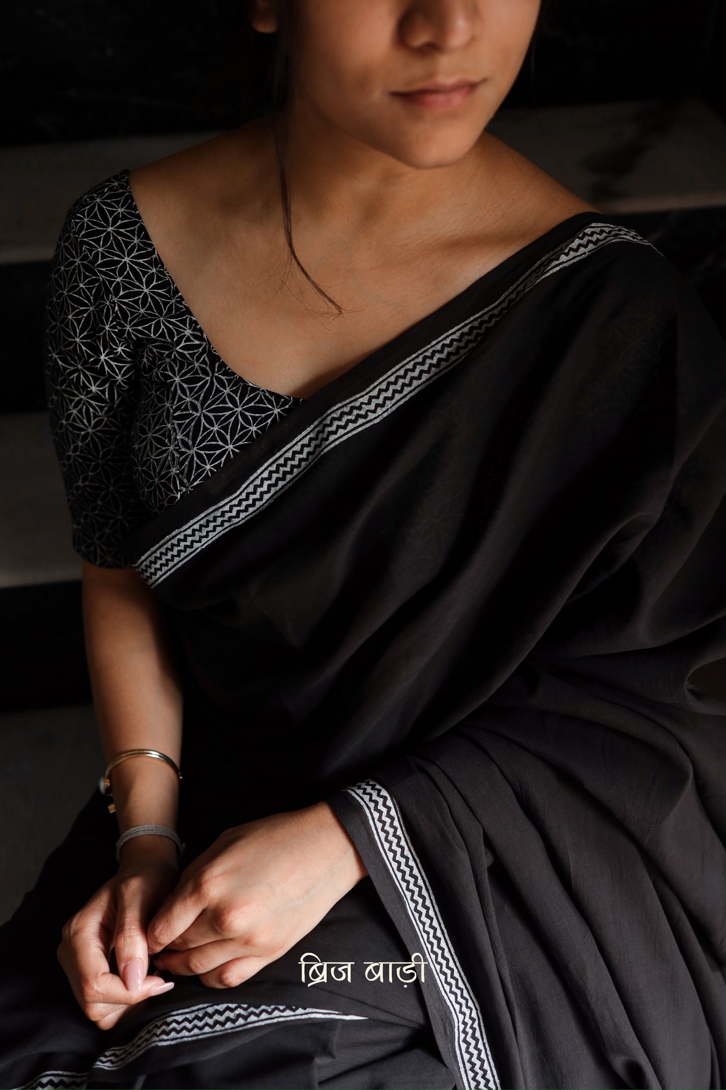 Black soft and light-weight cotton saree by Brij Bari with a simple and elegant hand block printed border in white for a timeless minimal look. Made from breathable, easy-to-drape cotton, this saree is perfect for everyday wear, offering effortless style & comfort. Pallu is finished with handmade mustard thread tassels, adding a handcrafted detail and a pop of colour. Includes a free hand block printed blouse piece designed to complement the sar the saree’s clean, classic border design.