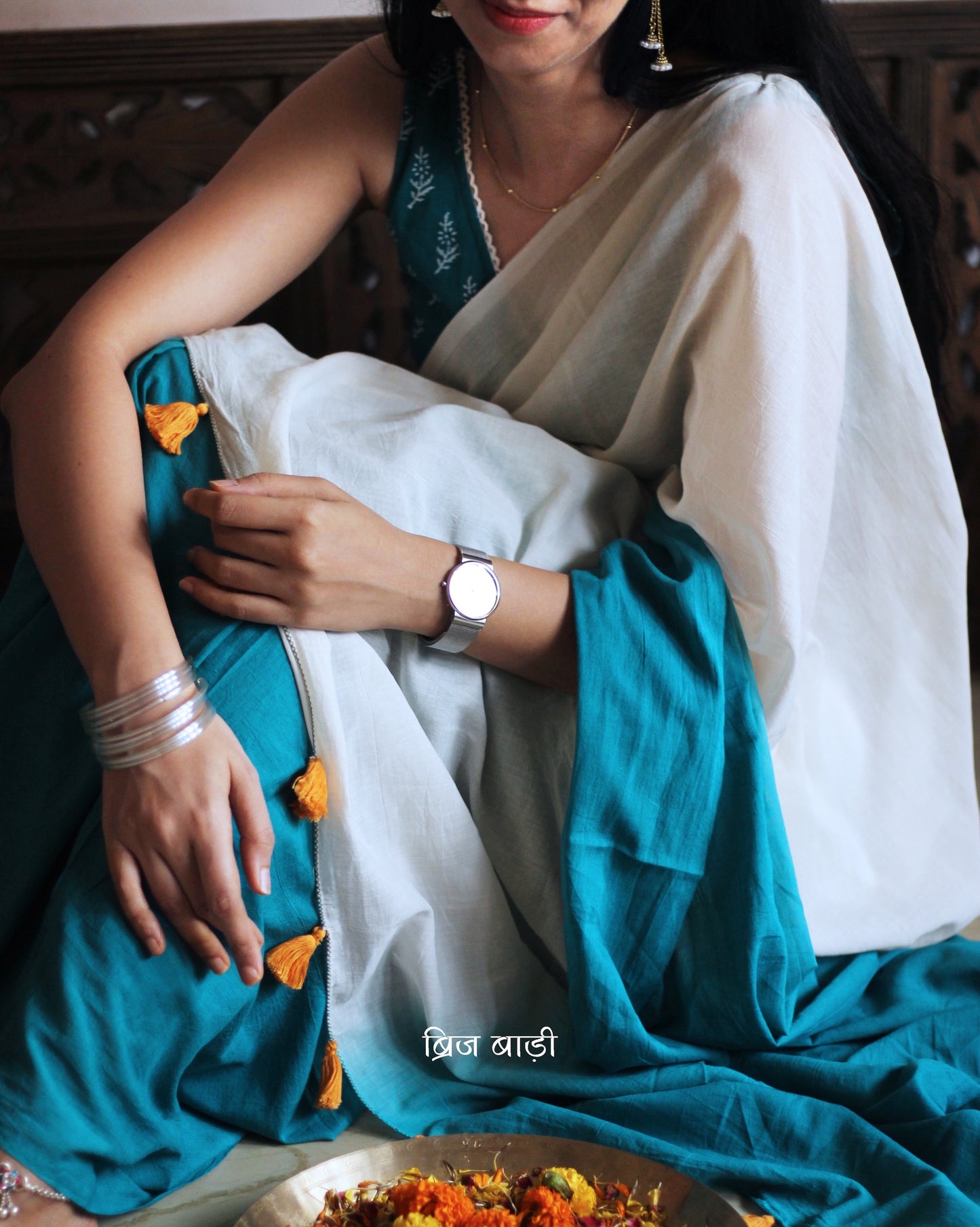 Teal Blue and off-white ombré soft cotton saree by Brij Bari, crafted for effortless elegance and all-day comfort. The subtle blend of tones adds fluidity and grace to the drape, making it perfect for both everyday wear and special occasions. The pallu is adorned with handcrafted orange thread tassels, lending a warm, artisanal touch. It comes with a free hand block printed blouse piece that complements the saree’s minimal yet striking aesthetic. Available in 8 beautiful colour options