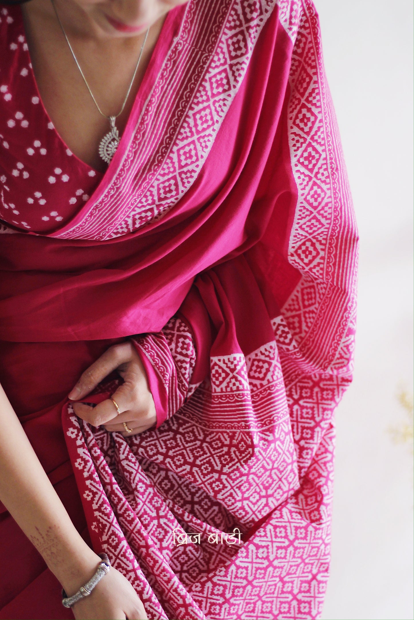 Soft and light-weight pink cotton saree by Brij Bari with intricate hand block printed detailing on the border and pallu for a refined, everyday aesthetic. Designed for effortless draping and breathable comfort this versatile saree is perfect for workdays, casual outings or understated occasions. Finished with delicate light blue handmade thread tassels on the pallu and paired with a free hand block printed blouse piece. A beautifully handcrafted daily wear staple from Brij Bari with free shipping pan India