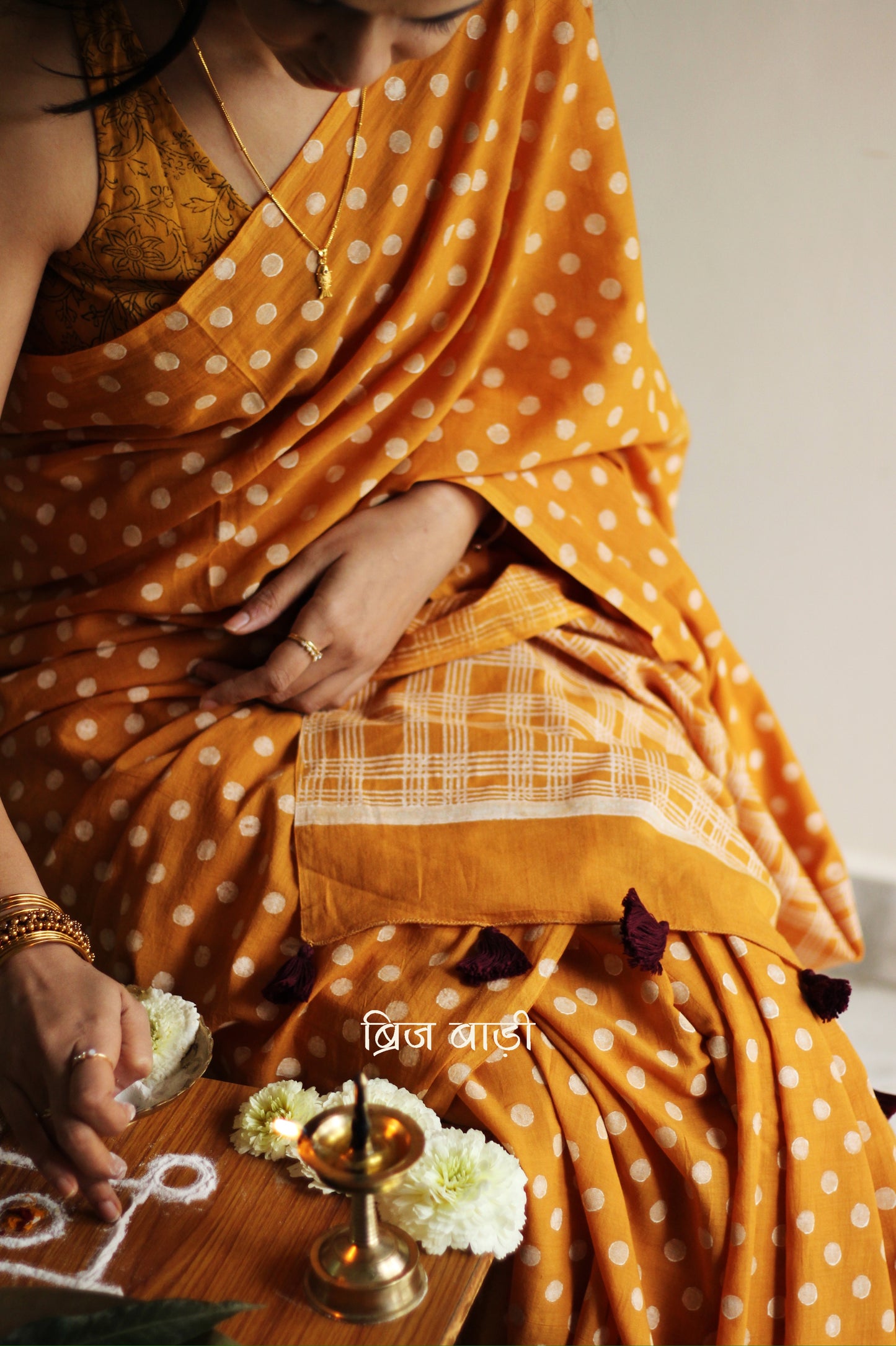 Yellow cotton saree with hand block printed polka dots, detailed with handmade thread tassels on the pallu. Includes a free soft cotton printed blouse piece.
