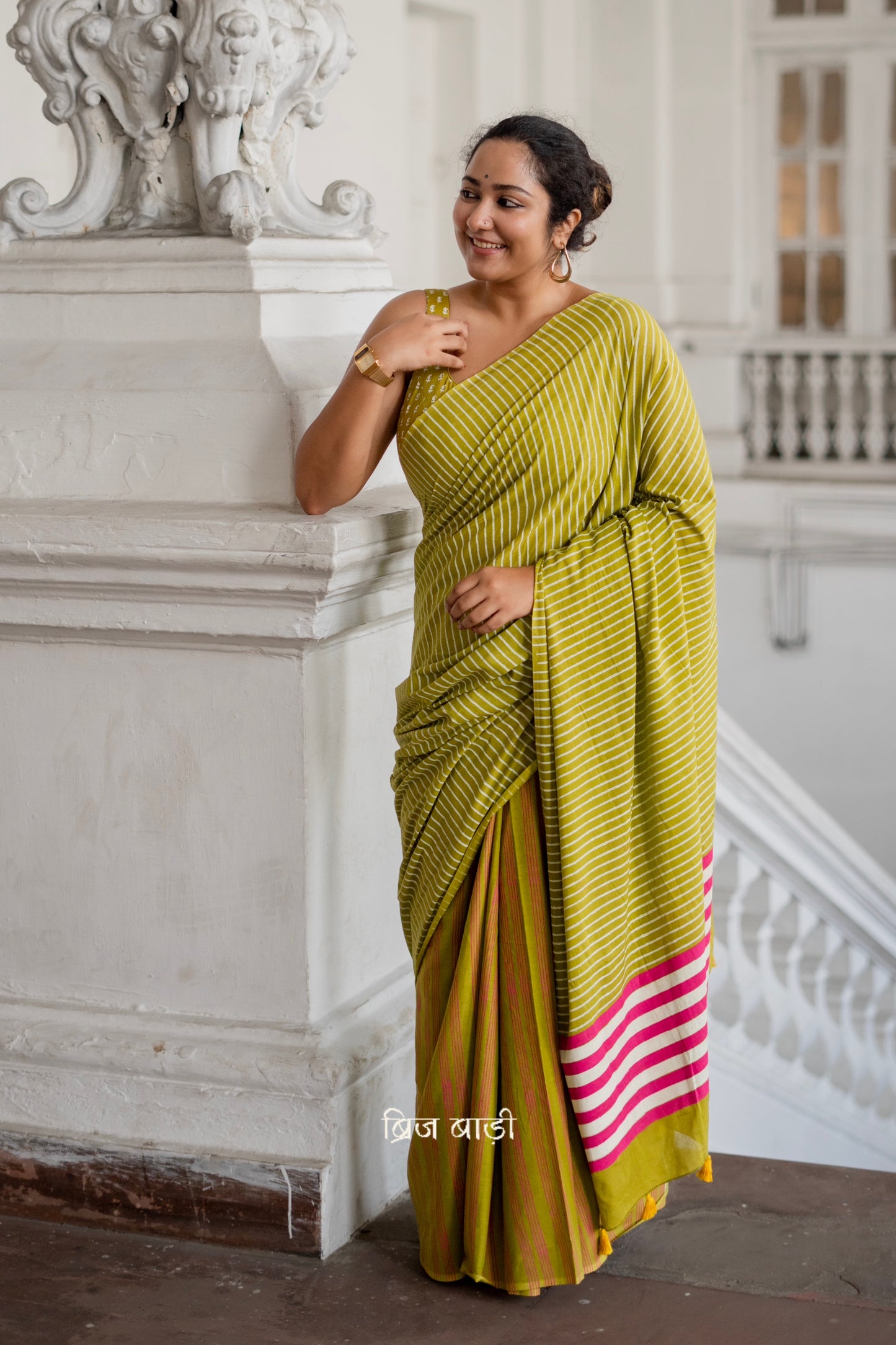 Light green soft and lightweight cotton saree by Brij Bari, hand block printed with pink and white stripe pattern. Finished with handmade yellow thread tassels on the pallu. Includes a free block printed cotton blouse piece. A versatile saree designed to add a vibrant pop of colour to your everyday wardrobe while ensuring breathable comfort and effortless style. Free shipping pan India.