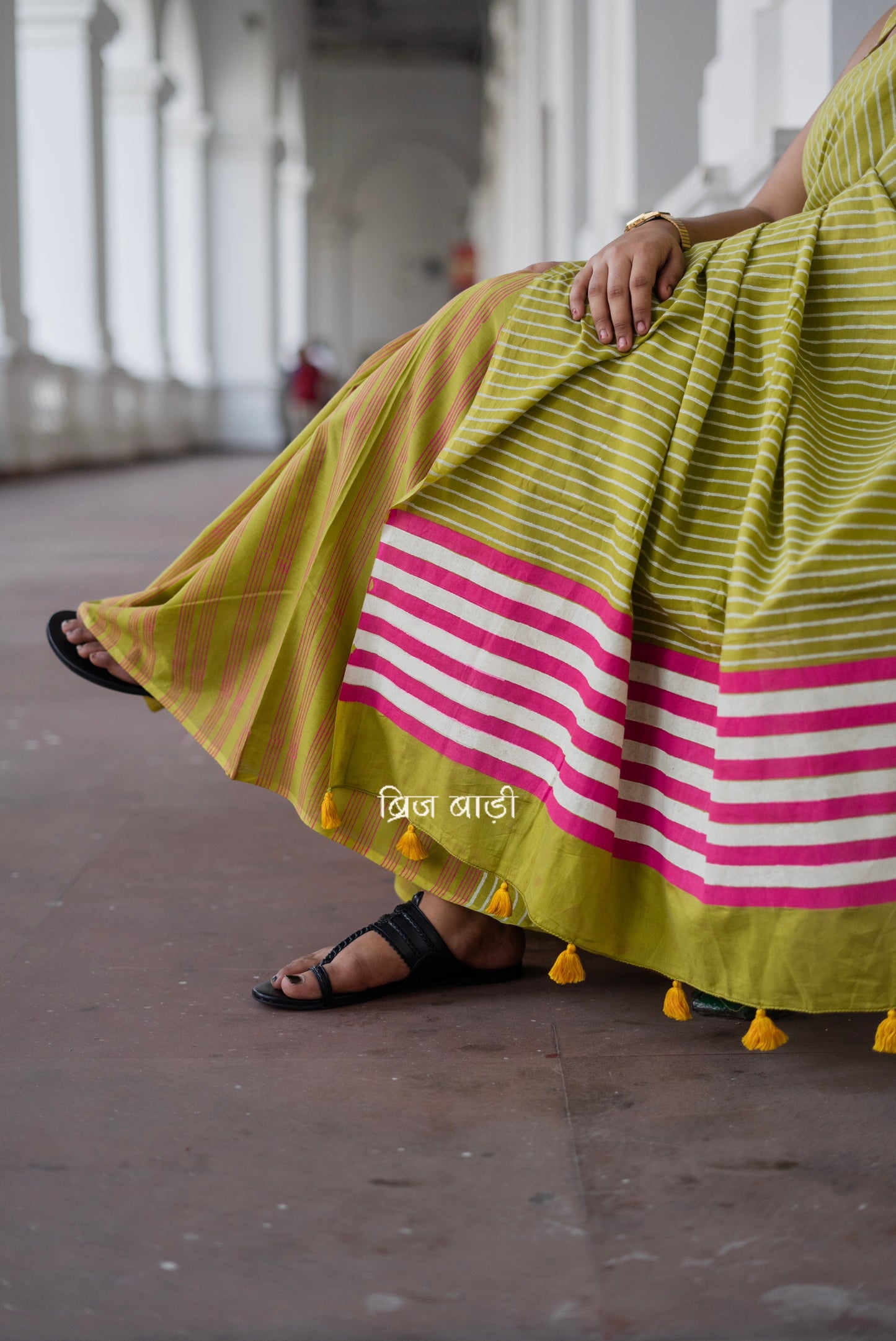 Light green soft and lightweight cotton saree by Brij Bari, hand block printed with pink and white stripe pattern. Finished with handmade yellow thread tassels on the pallu. Includes a free block printed cotton blouse piece. A versatile saree designed to add a vibrant pop of colour to your everyday wardrobe while ensuring breathable comfort and effortless style. Free shipping pan India.