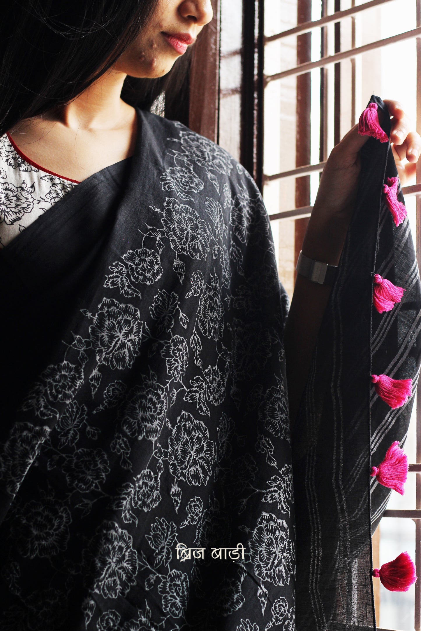 Black soft and light-weight cotton saree by Brij Bari, hand block printed with a graceful rose pattern on the skirt and contrasting bold stripes on the pallu. This versatile, breathable saree is designed for everyday ease — lightweight, elegant, and comfortable, perfect for casual outings & office wear. Finished with charming pink handmade thread tassels on the pallu. Comes with a free hand block printed blouse piece designed to compliment the sare’s floral and striped patterns. Free shipping pan India.