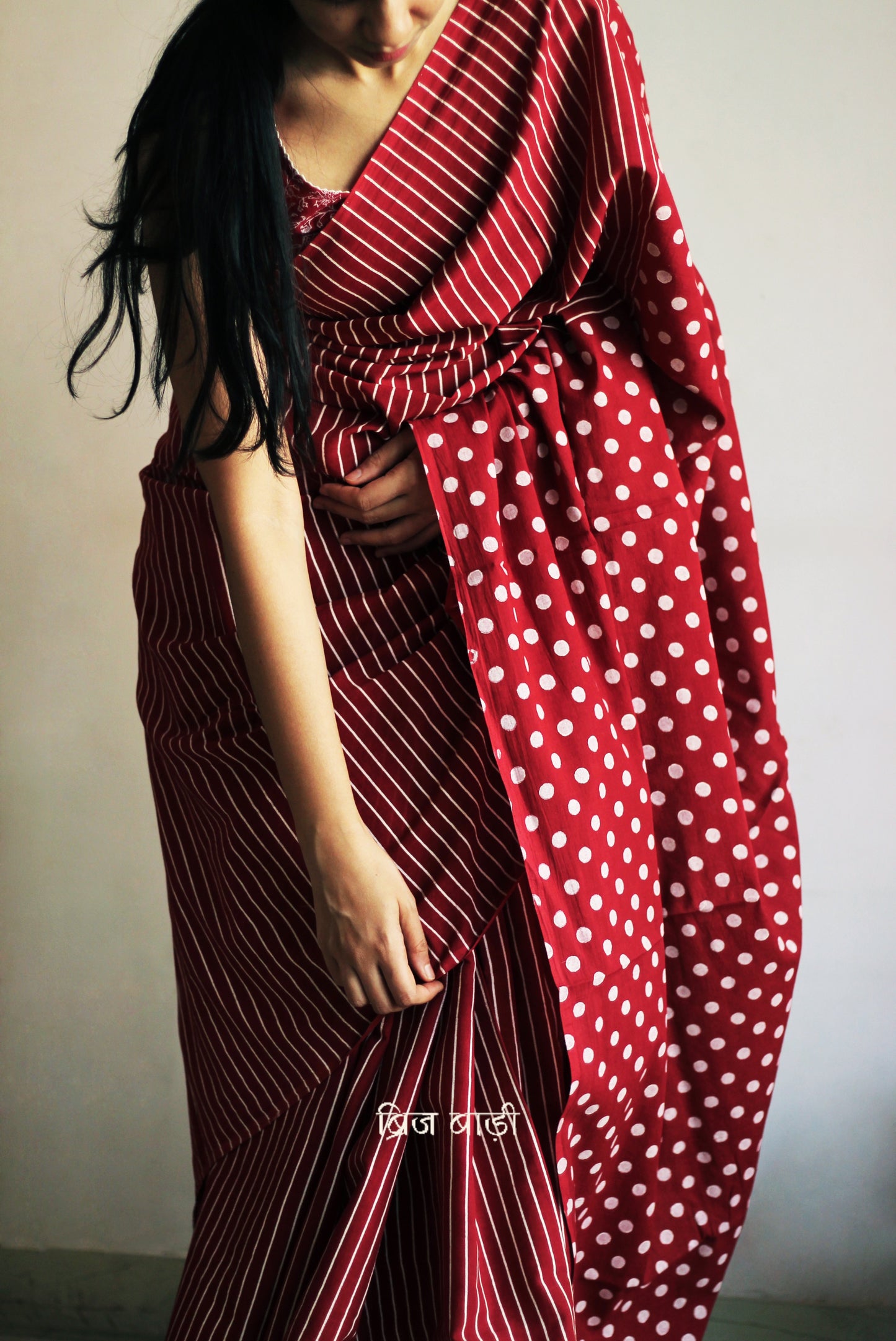 Deep red cotton saree by Brij Bari with bold hand block printed stripe and polka dot design. Artisan-crafted, breathable fabric with matching blouse piece.