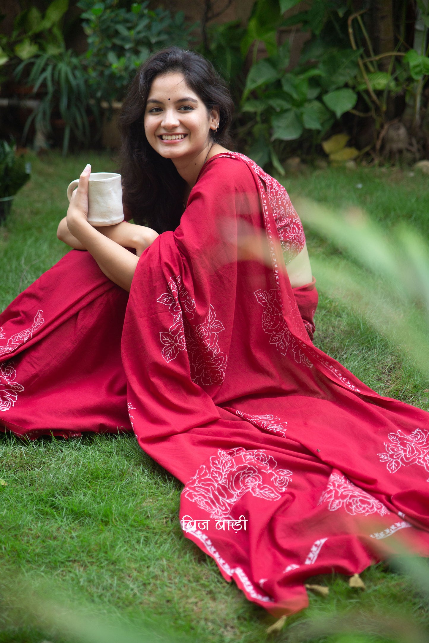 Deep red buttery soft and lightweight cotton saree by Brij Bari, hand block printed with delicate white rose motifs for a refined, artisanal touch. The pallu is finished with olive green handmade thread tassels that add a subtle contrast and handcrafted charm. Comes with a free coordinated block printed blouse piece. Designed for all-day comfort and understated elegance, this saree is a versatile pick for everyday wear or casual occasions. Free shipping pan India.