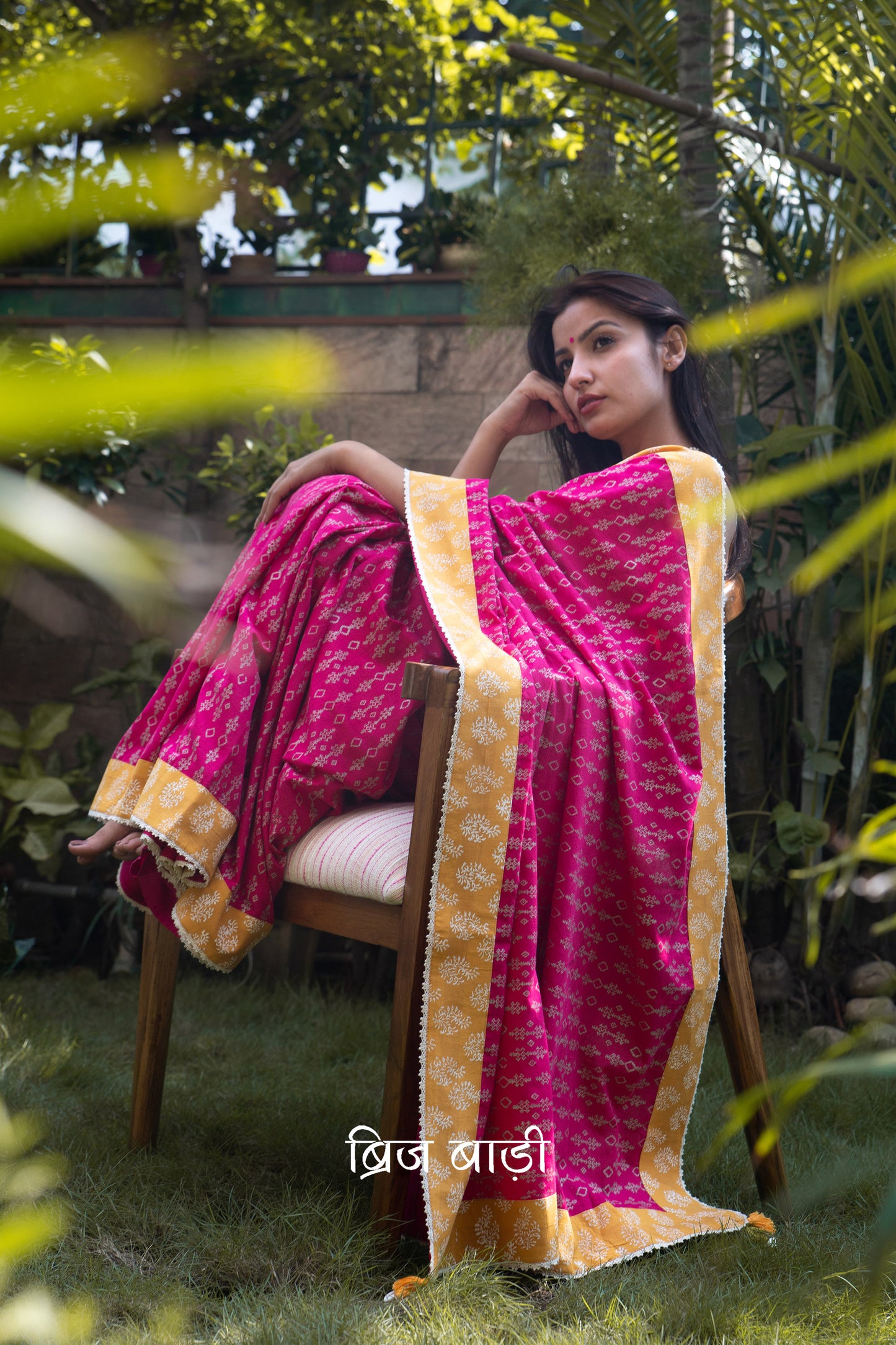 Pink cotton saree by Brij Bari, hand block printed with a delicate geometrical pattern in silver, beautifully contrasted with an ochre yellow block printed border. The saree is finished with fine crochet lace detailing and adorned with handmade orange and light green thread tassels on the pallu corner, accented with decorative sea shells. A standout festive or special occasion saree designed for both style and comfort. Comes with a free block printed blouse piece. Free shipping pan India.