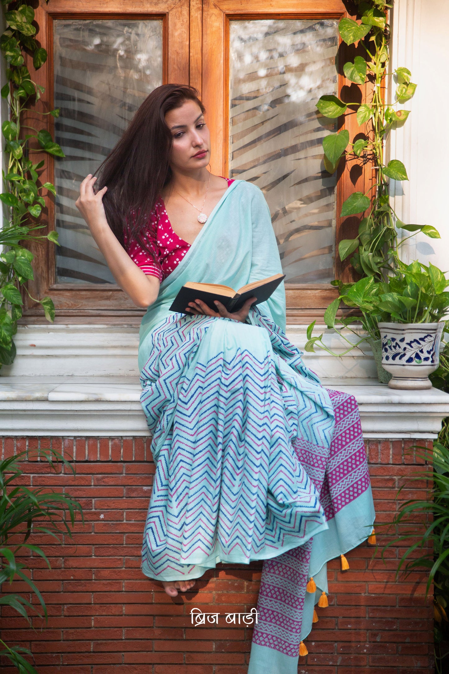 Sky blue, buttery soft, and lightweight cotton saree by Brij Bari, hand block printed with vibrant multicolor chevron patterns on the skirt and a geometrical pink design on the pallu. The saree is detailed with handmade orange thread tassels on the pallu, adding a pop of color and handcrafted charm. It comes with a free block-printed blouse piece. Perfect for all-day comfort, the saree is designed to blend style and ease, making it ideal for casual or semi-formal occasions. Free shipping pan India.