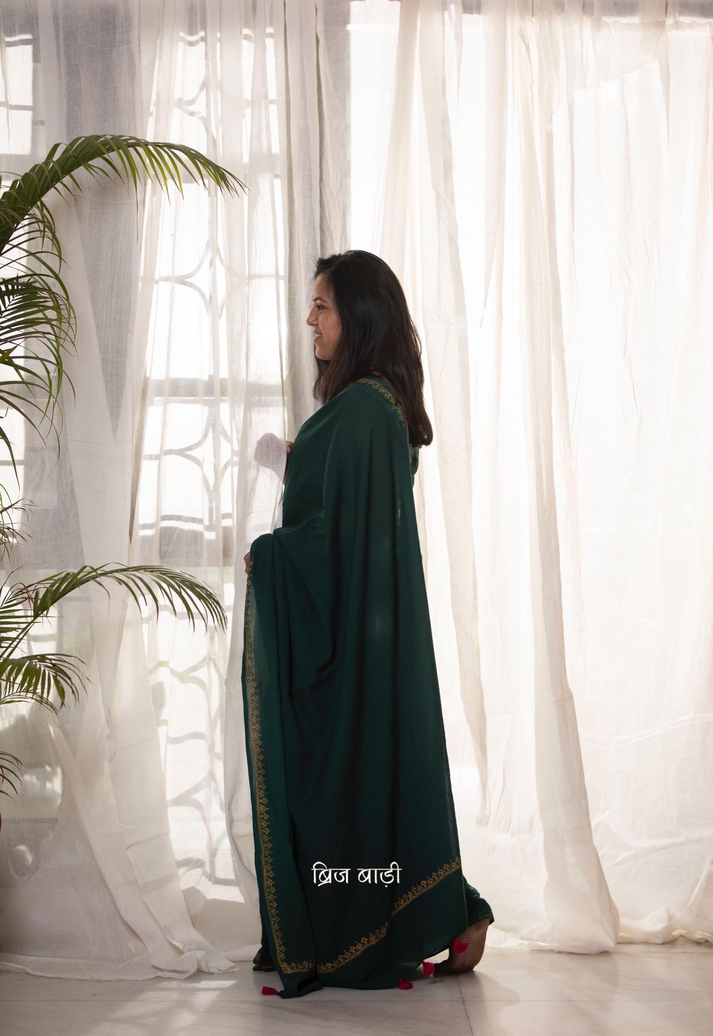 Deep green soft and light-weight cotton saree by Brij Bari, featuring a delicate hand block printed border in vibrant ochre yellow that contrasts beautifully with the rich green. The saree is finished with pink handmade thread tassels on the pallu, adding a touch of traditional charm. It comes with a free matching block printed blouse piece, completing the handcrafted look. Perfect for everyday wear, casual outings, or semi-formal occasions, with free shipping pan India.