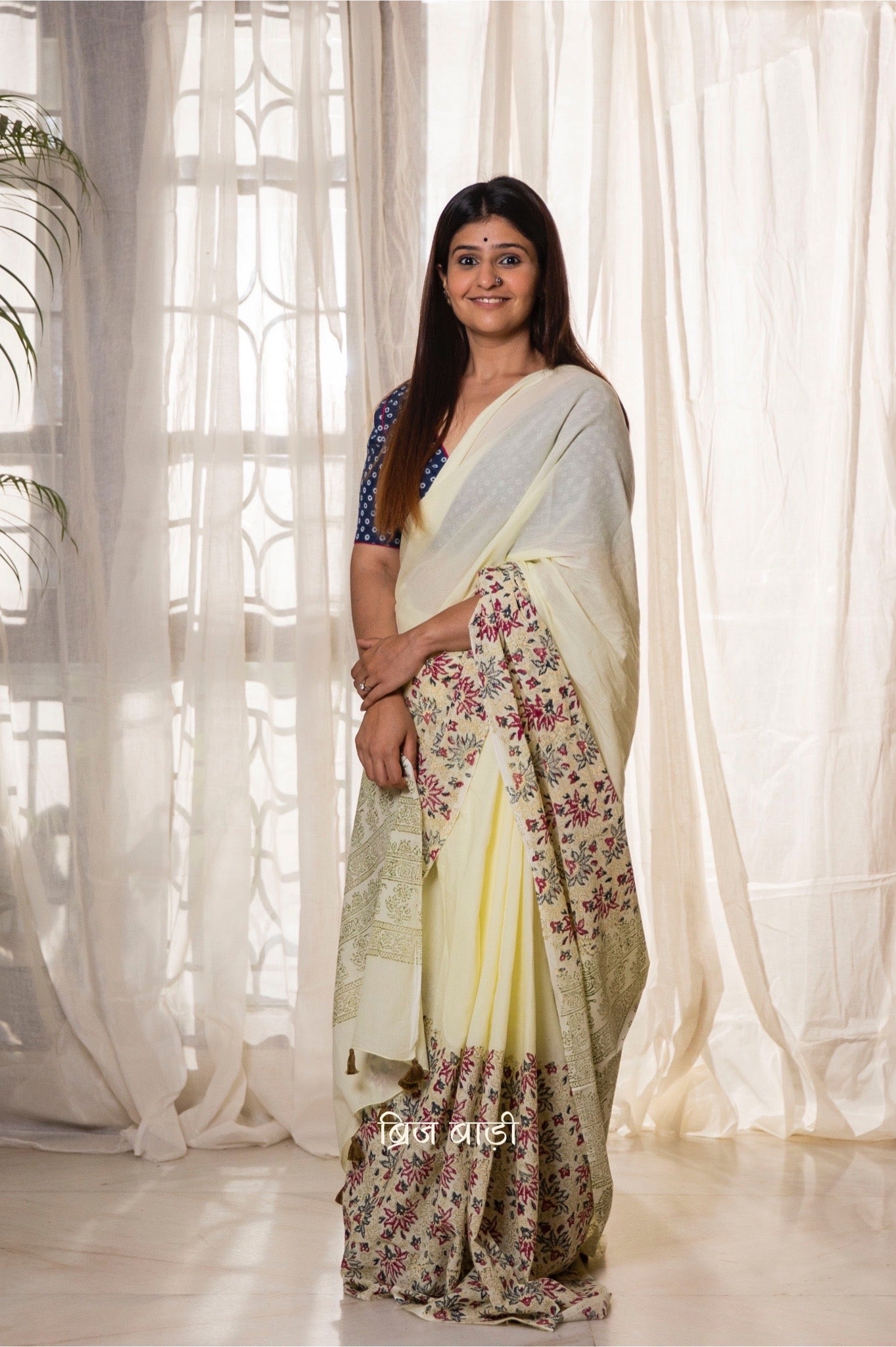 Pastel yellow buttery soft and light-weight cotton saree by Brij Bari, featuring a delicate and intricate multicolour floral hand block print on the skirt, complemented by an olive green floral pattern on the pallu. Detailed with olive green handmade thread tassels on the pallu, this saree comes with a free matching block printed blouse piece. Designed for all-day comfort, effortless elegance, and versatile styling. Free shipping available pan India.