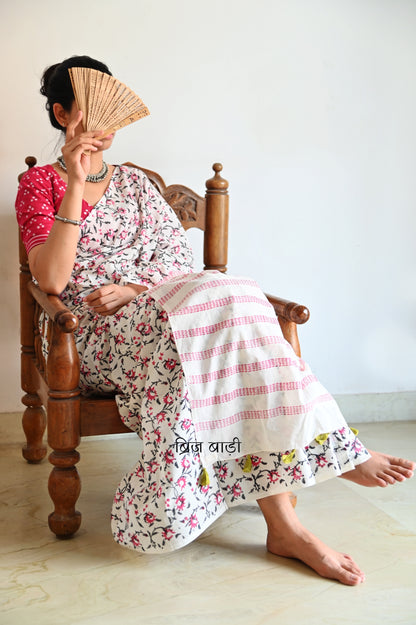 Off-white soft cotton saree by Brij Bari, hand block printed by skilled artisans with a striking floral pattern in pink and black for a fresh, elegant appeal. The saree is light-weight and breathable—ideal for summer wear and everyday comfort. The pallu is detailed with handcrafted light green thread tassels, adding a subtle yet artistic finishing touch. Comes with a free hand block printed blouse piece that complements the saree’s colour palette. A versatile, handcrafted piece perfect for daily wear