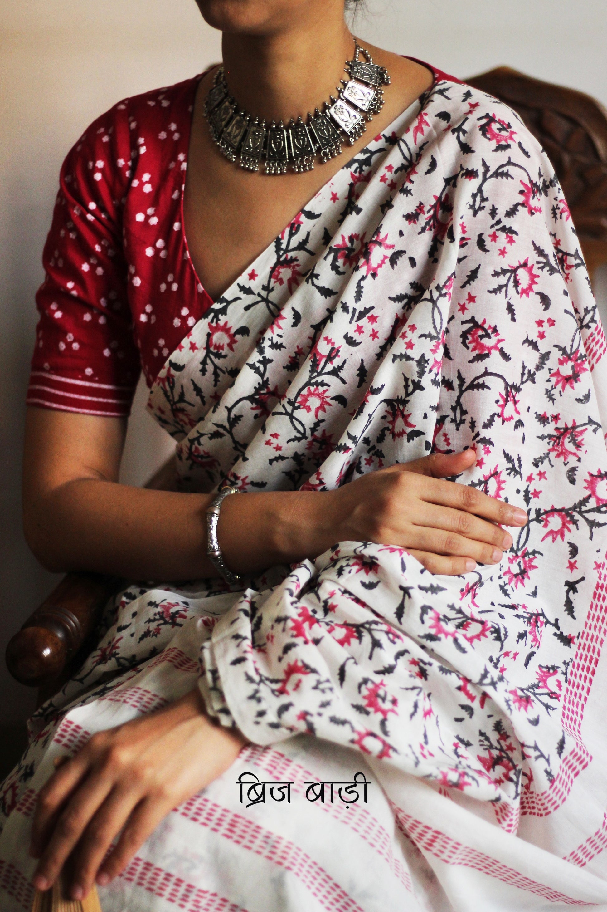 Off-white soft cotton saree by Brij Bari, hand block printed by skilled artisans with a striking floral pattern in pink and black for a fresh, elegant appeal. The saree is light-weight and breathable—ideal for summer wear and everyday comfort. The pallu is detailed with handcrafted light green thread tassels, adding a subtle yet artistic finishing touch. Comes with a free hand block printed blouse piece that complements the saree’s colour palette. A versatile, handcrafted piece perfect for daily wear