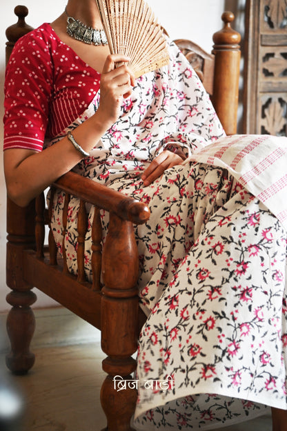 Off-white soft cotton saree by Brij Bari, hand block printed by skilled artisans with a striking floral pattern in pink and black for a fresh, elegant appeal. The saree is light-weight and breathable—ideal for summer wear and everyday comfort. The pallu is detailed with handcrafted light green thread tassels, adding a subtle yet artistic finishing touch. Comes with a free hand block printed blouse piece that complements the saree’s colour palette. A versatile, handcrafted piece perfect for daily wear