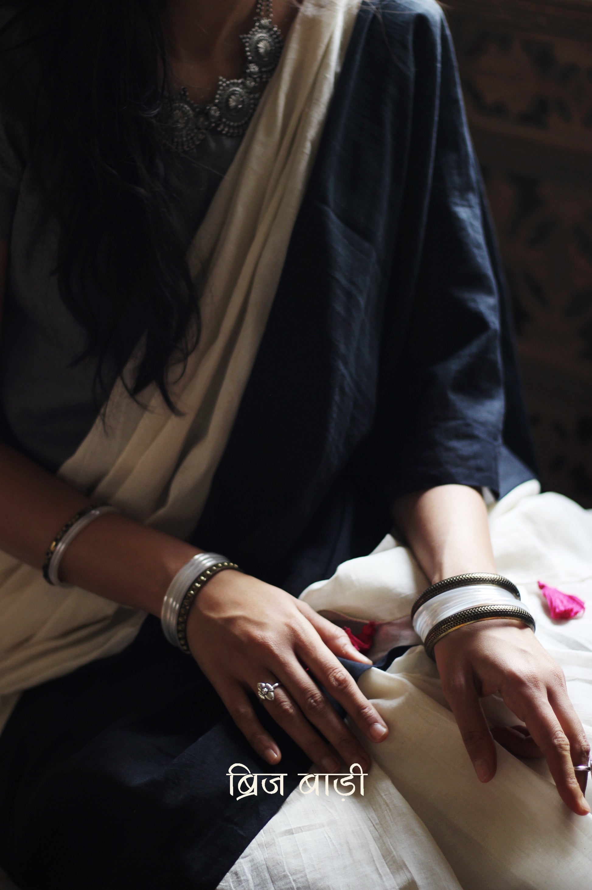 Black and off-white ombré soft cotton saree by Brij Bari, crafted for effortless elegance and all-day comfort. The subtle blend of tones adds fluidity and grace to the drape, making it perfect for both everyday wear and special occasions. The pallu is adorned with handcrafted pink thread tassels, lending a warm, artisanal touch. It comes with a free hand block printed blouse piece that complements the saree’s minimal yet striking aesthetic. Available in 8 beautiful colour options