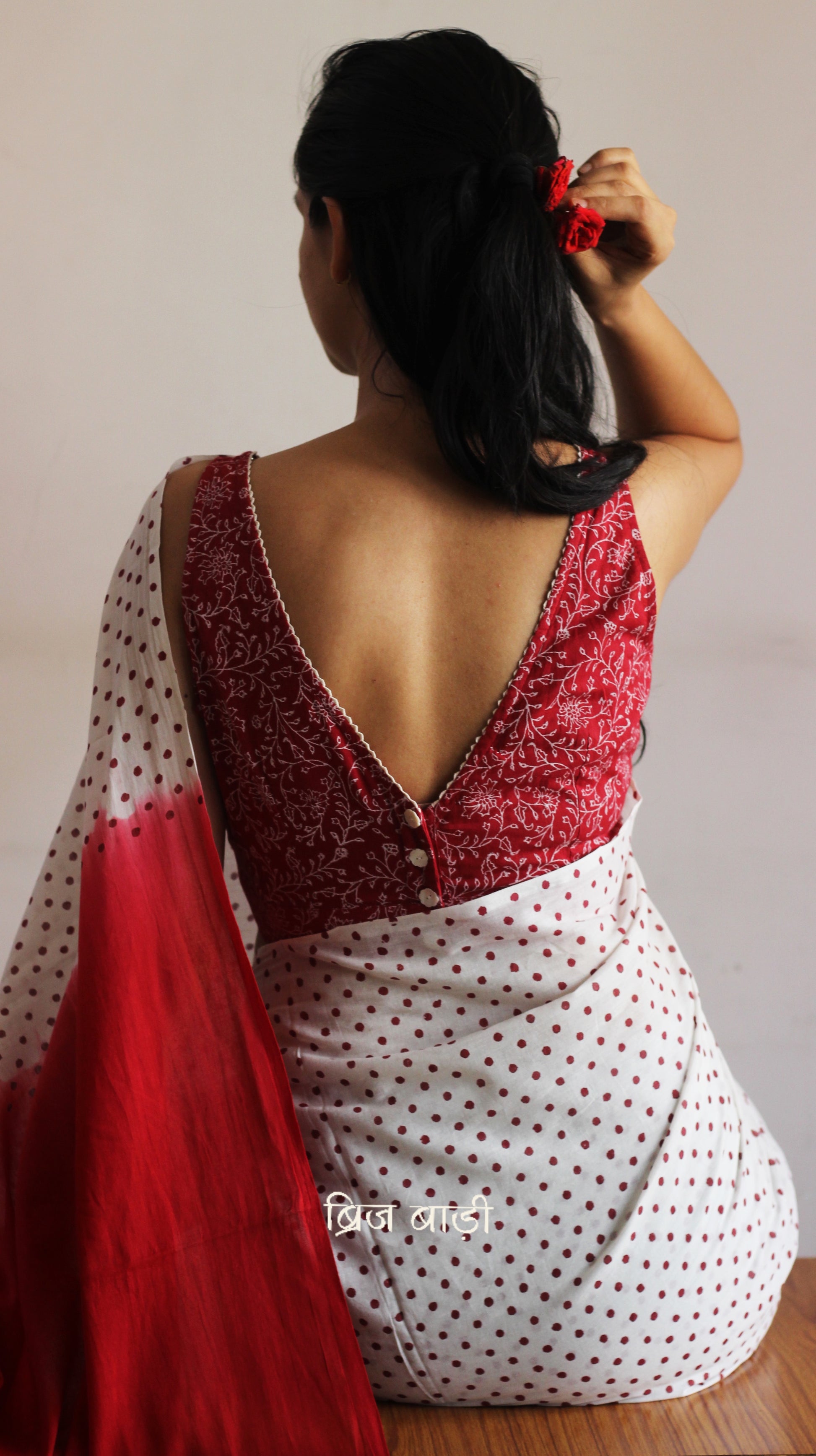 Off-white soft and light-weight cotton saree by Brij Bari, featuring deep red ombre pallu and small retro-style polka dot hand block prints. Accented with handcrafted mustard thread tassels on the pallu for a touch of artisanal charm. Includes a free matching hand block printed blouse piece. A timeless piece combining elegance, tradition, and comfort—crafted by Brij Bari’s skilled artisans.