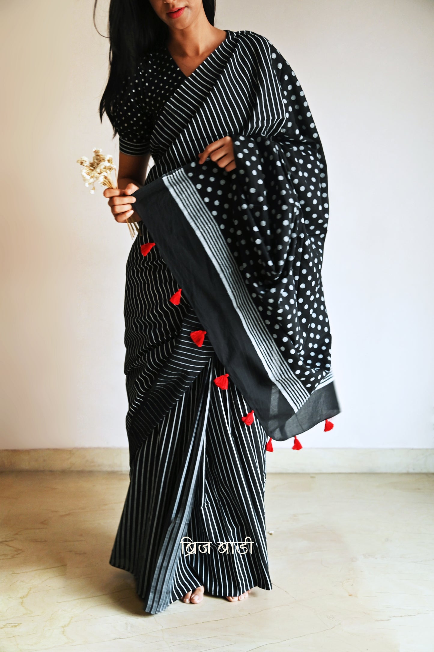 Black cotton saree by Brij Bari with bold hand block printed stripe and polka dot design. Artisan-crafted, breathable fabric with matching blouse piece.


