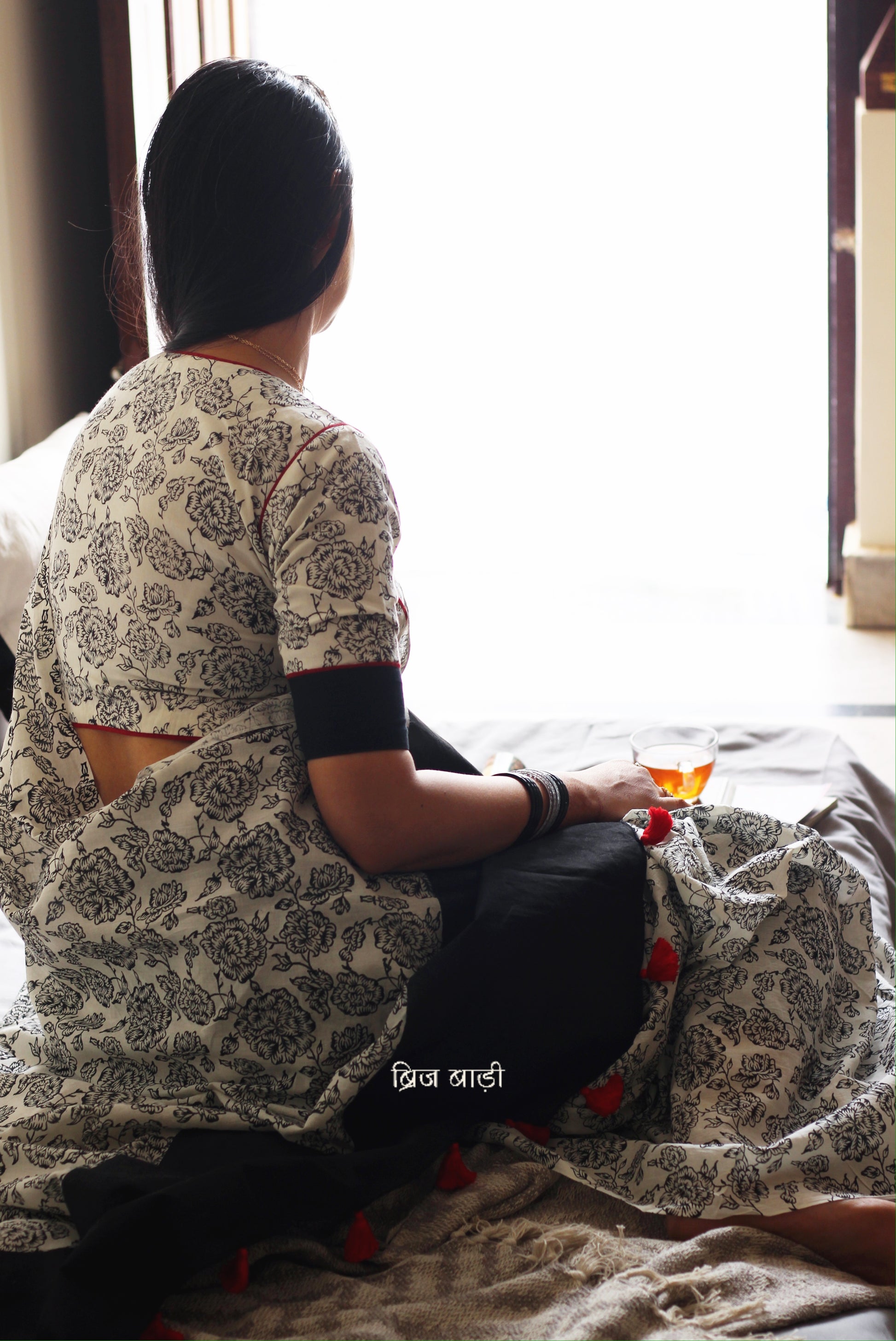 Off-white soft and light-weight cotton saree by Brij Bari, hand block printed with a delicate rose pattern for an elegant, understated everyday look. Crafted from breathable cotton, this saree ensures comfort and ease of wear, ideal for workdays, casual gatherings or daily summer dressing. The pallu is finished with red handmade thread tassels adding a traditional handcrafted detail to the look. Comes with a free hand block printed blouse piece designed to perfectly compliment the saree. 
