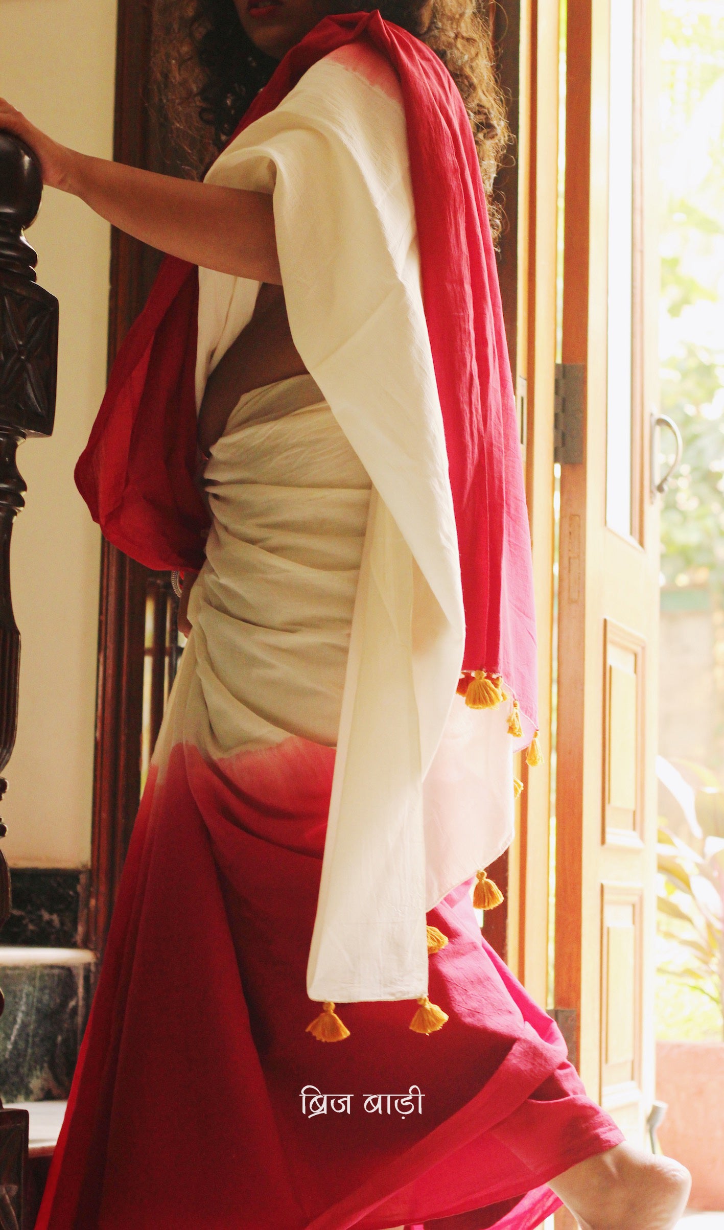 Red and off-white ombré soft cotton saree by Brij Bari, crafted for effortless elegance and all-day comfort. The subtle blend of tones adds fluidity and grace to the drape, making it perfect for both everyday wear and special occasions. The pallu is adorned with handcrafted mustard thread tassels, lending a warm, artisanal touch. It comes with a free hand block printed blouse piece that complements the saree’s minimal yet striking aesthetic. Available in 8 beautiful colour options