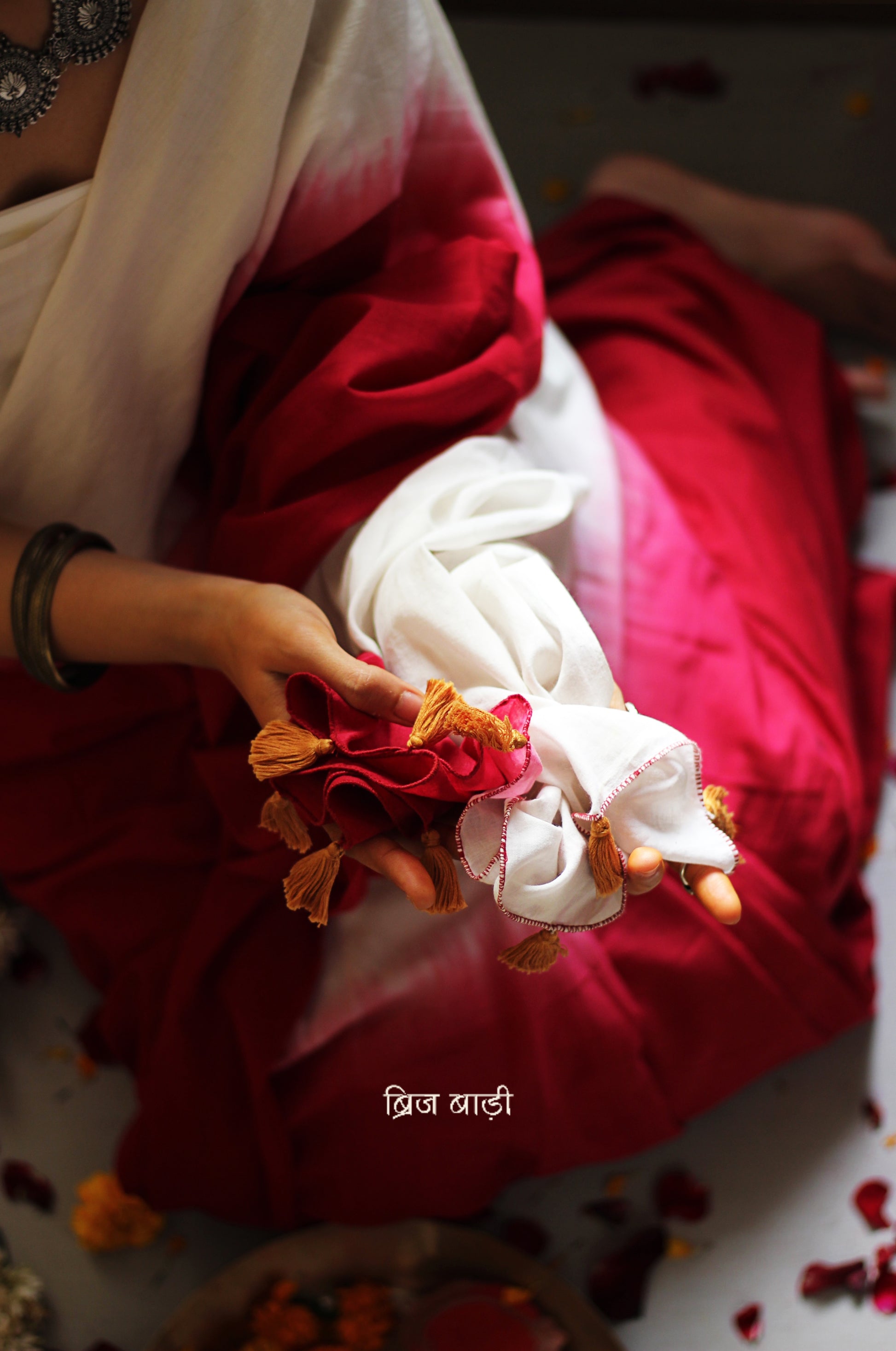 Red and off-white ombré soft cotton saree by Brij Bari, crafted for effortless elegance and all-day comfort. The subtle blend of tones adds fluidity and grace to the drape, making it perfect for both everyday wear and special occasions. The pallu is adorned with handcrafted mustard thread tassels, lending a warm, artisanal touch. It comes with a free hand block printed blouse piece that complements the saree’s minimal yet striking aesthetic. Available in 8 beautiful colour options