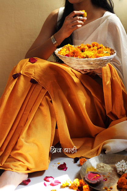 Yellow and off-white ombré soft cotton saree by Brij Bari, crafted for effortless elegance and all-day comfort. The subtle blend of tones adds fluidity and grace to the drape, making it perfect for both everyday wear and special occasions. The pallu is adorned with handcrafted purple thread tassels, lending a warm, artisanal touch. It comes with a free hand block printed blouse piece that complements the saree’s minimal yet striking aesthetic. Available in 8 beautiful colour options