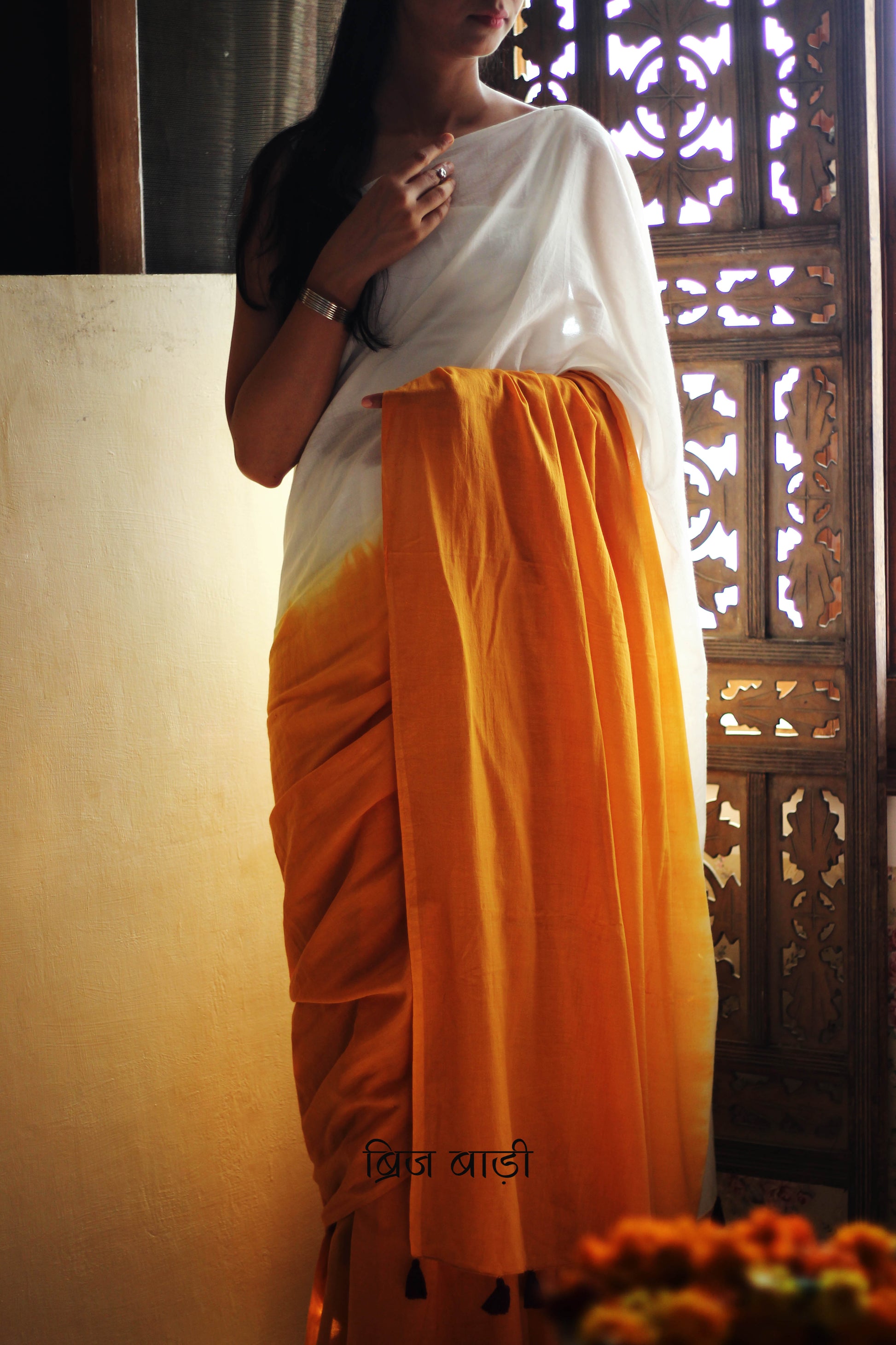 Yellow and off-white ombré soft cotton saree by Brij Bari, crafted for effortless elegance and all-day comfort. The subtle blend of tones adds fluidity and grace to the drape, making it perfect for both everyday wear and special occasions. The pallu is adorned with handcrafted purple thread tassels, lending a warm, artisanal touch. It comes with a free hand block printed blouse piece that complements the saree’s minimal yet striking aesthetic. Available in 8 beautiful colour options