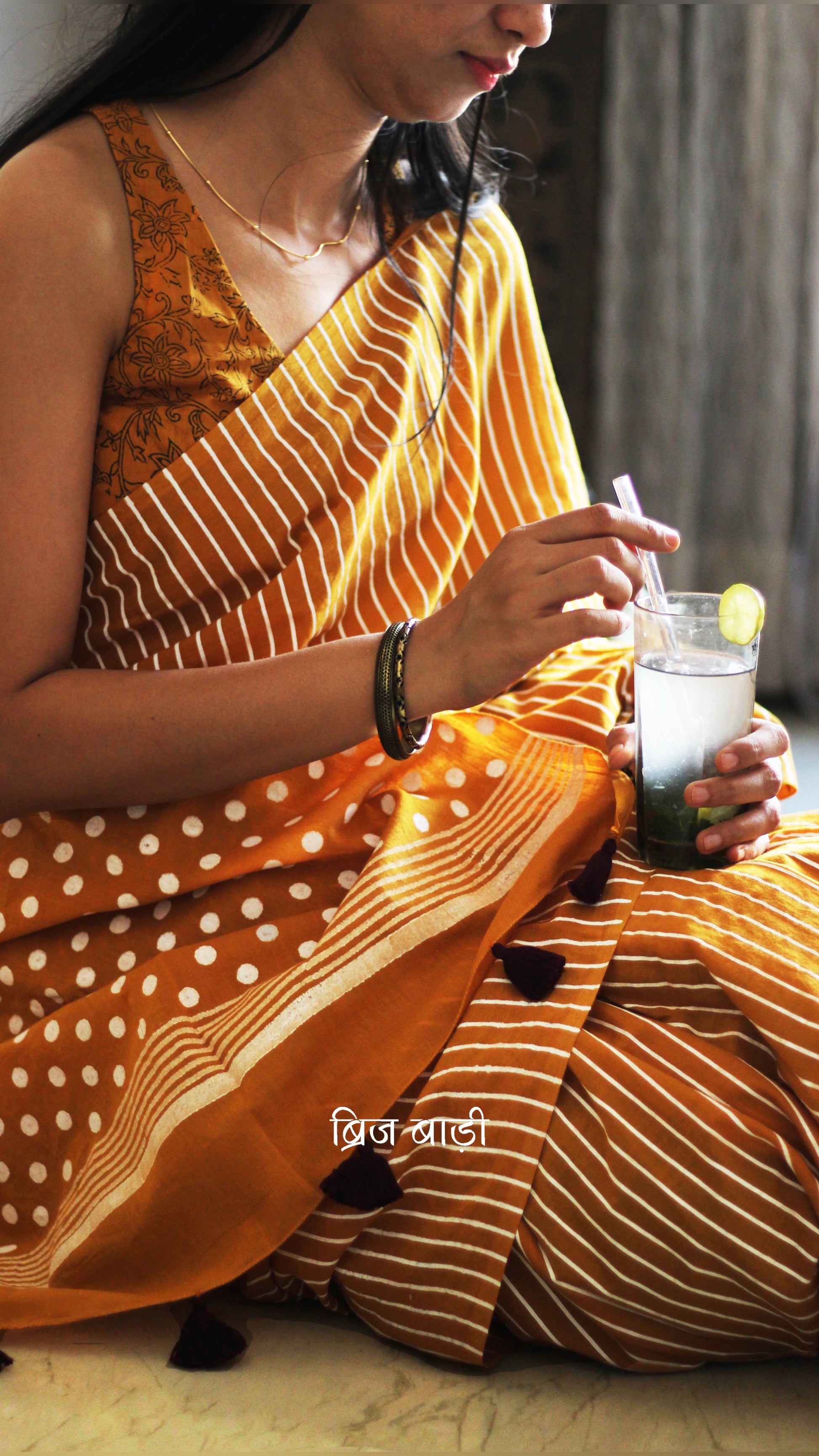 Yellow cotton saree by Brij Bari with bold hand block printed stripe and polka dot design. Artisan-crafted, breathable fabric with matching blouse piece.

