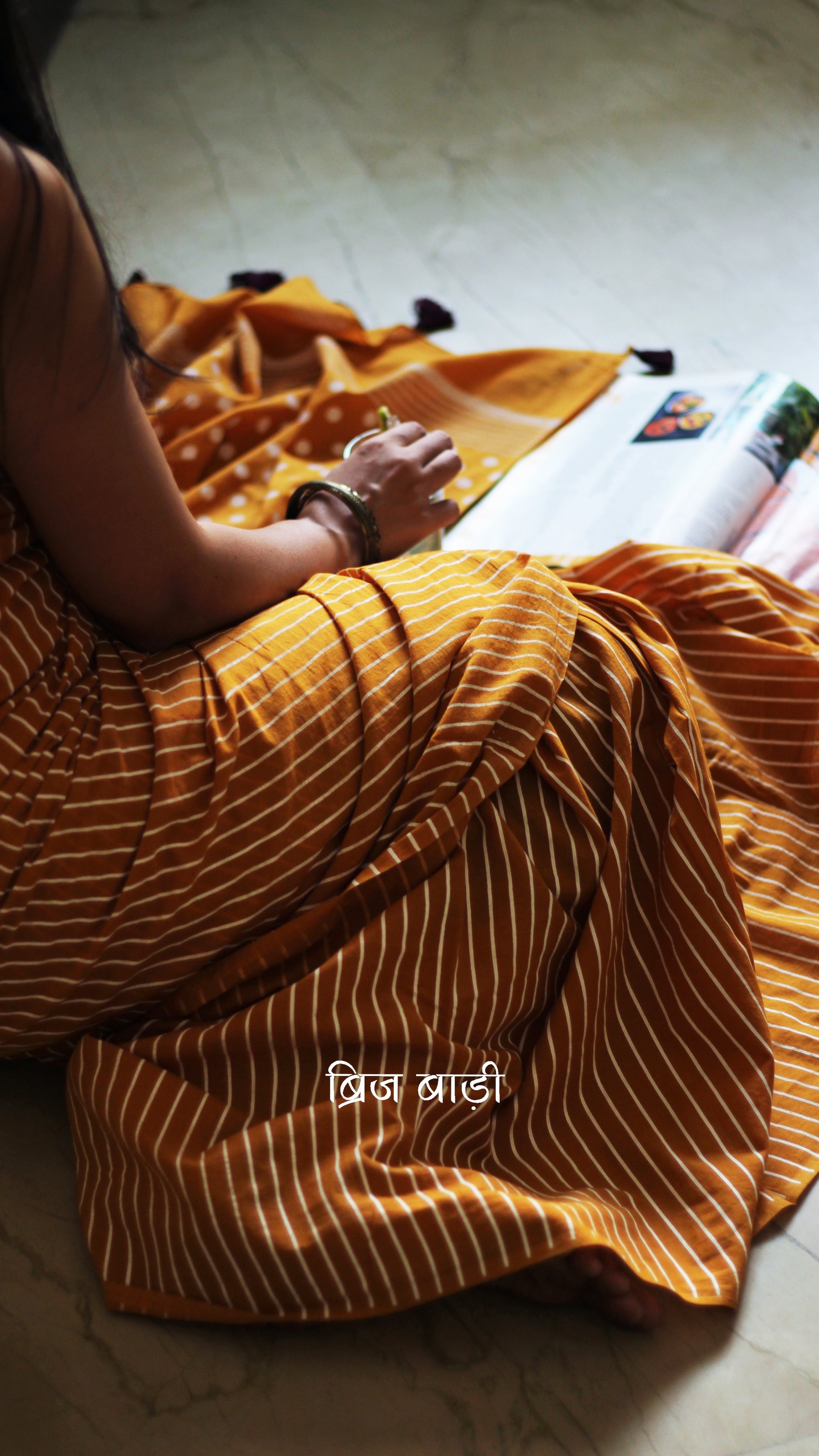 Yellow cotton saree by Brij Bari with bold hand block printed stripe and polka dot design. Artisan-crafted, breathable fabric with matching blouse piece.

