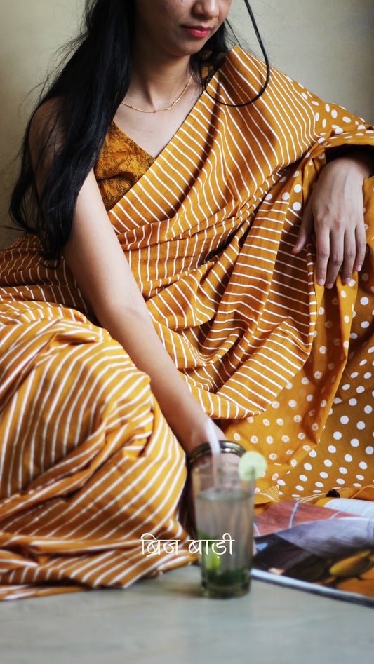 Yellow cotton saree with bold hand block printed stripes and polka dots, artisan-crafted in breathable fabric. Includes matching printed blouse piece.

