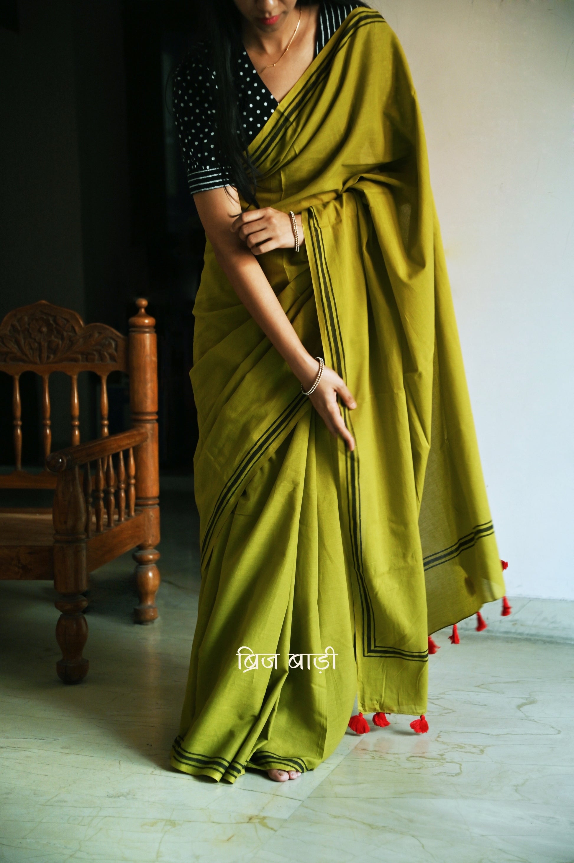 Light green soft and light-weight cotton saree by Brij Bari, crafted with a simple yet elegant black hand block printed stripe border. The saree is adorned with red handmade thread tassels on the pallu, adding a vibrant touch. It comes with a free matching block printed blouse piece, offering a complete handcrafted look. Available in 2 colours, designed for all-day comfort and style, perfect for casual and everyday wear. Free shipping available pan India.