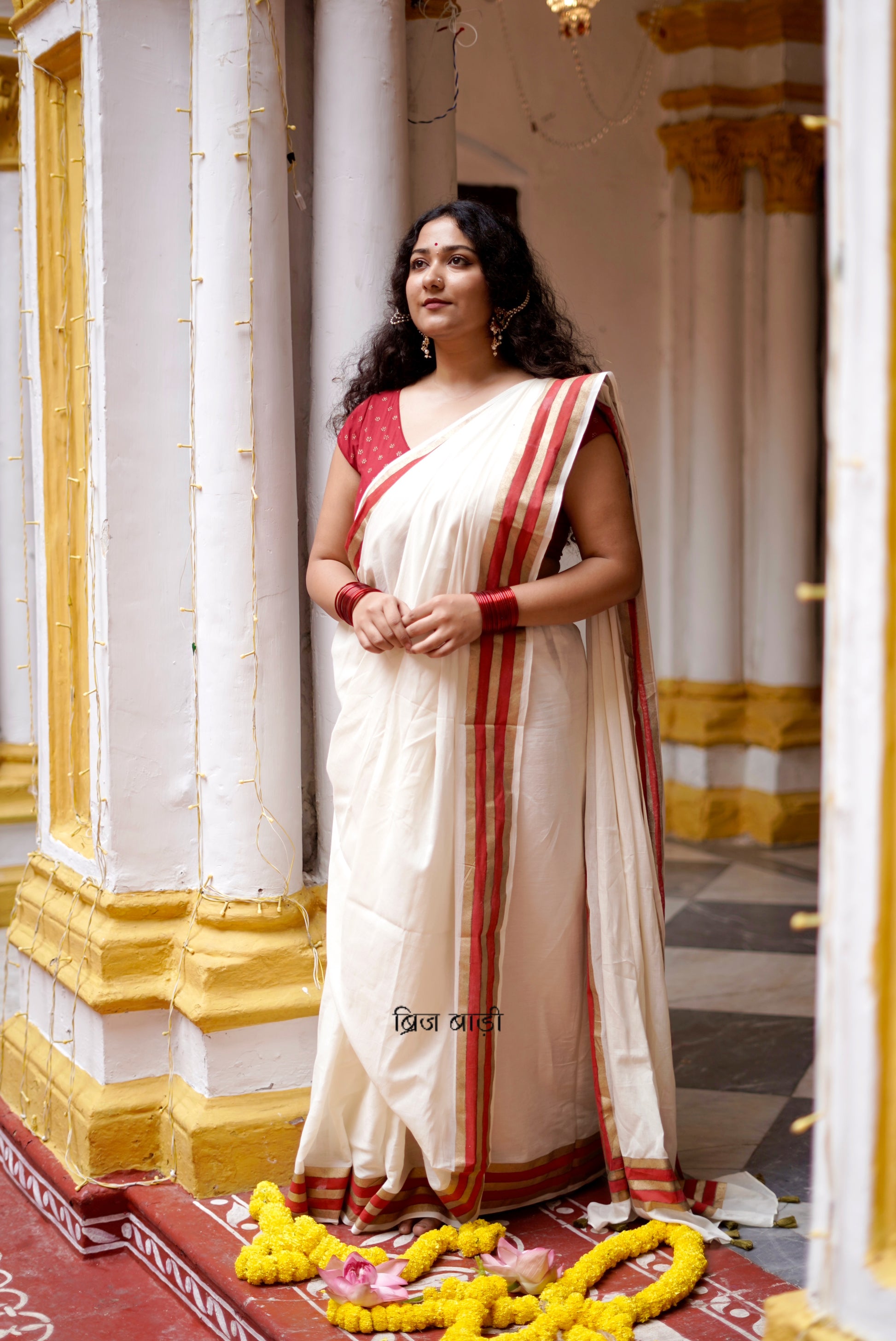 Saraswati off-white cotton saree with hand block printed gold and red stripe border and handmade thread tassels detailing on palla