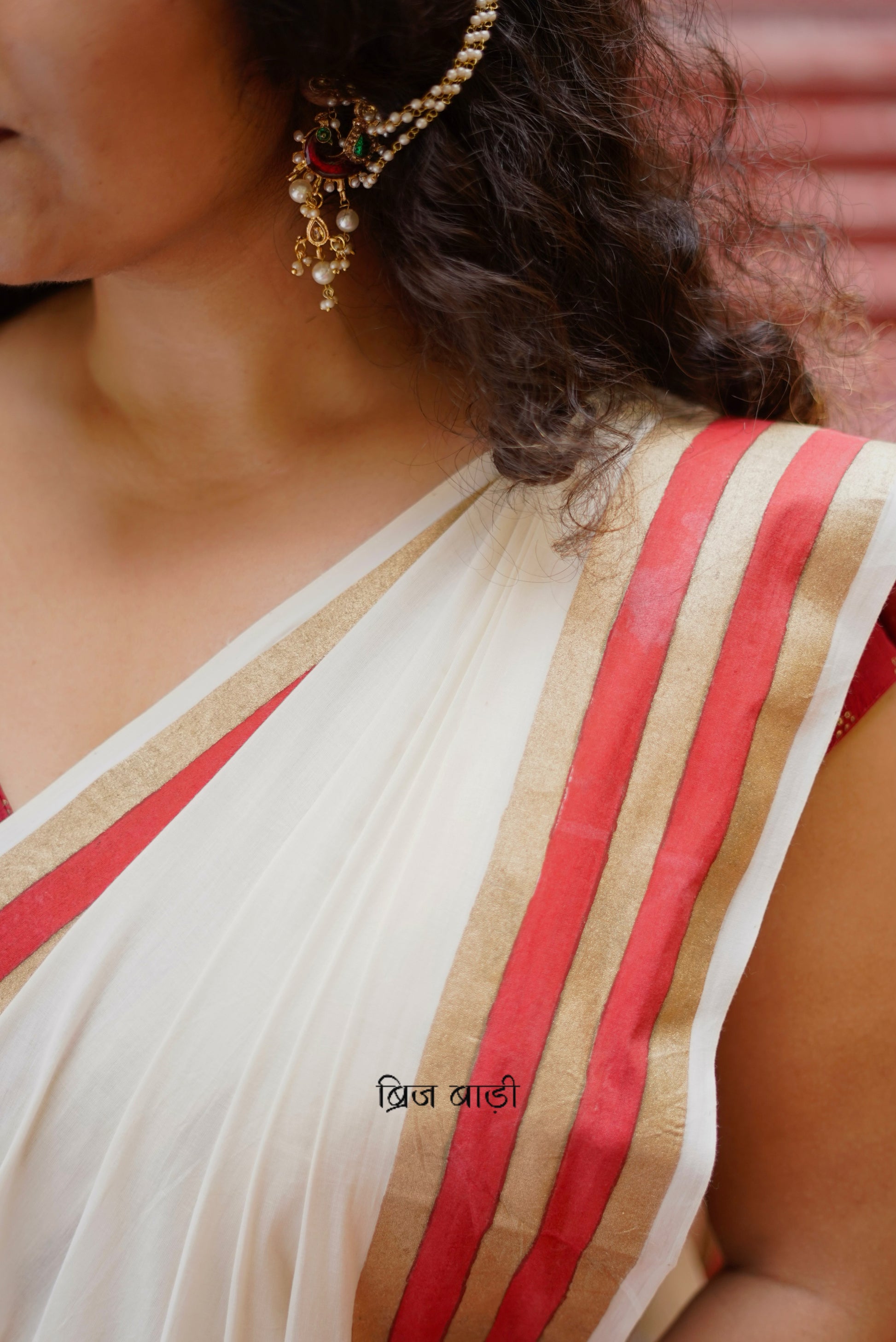 Saraswati off-white cotton saree with hand block printed gold and red stripe border and handmade thread tassels detailing on palla