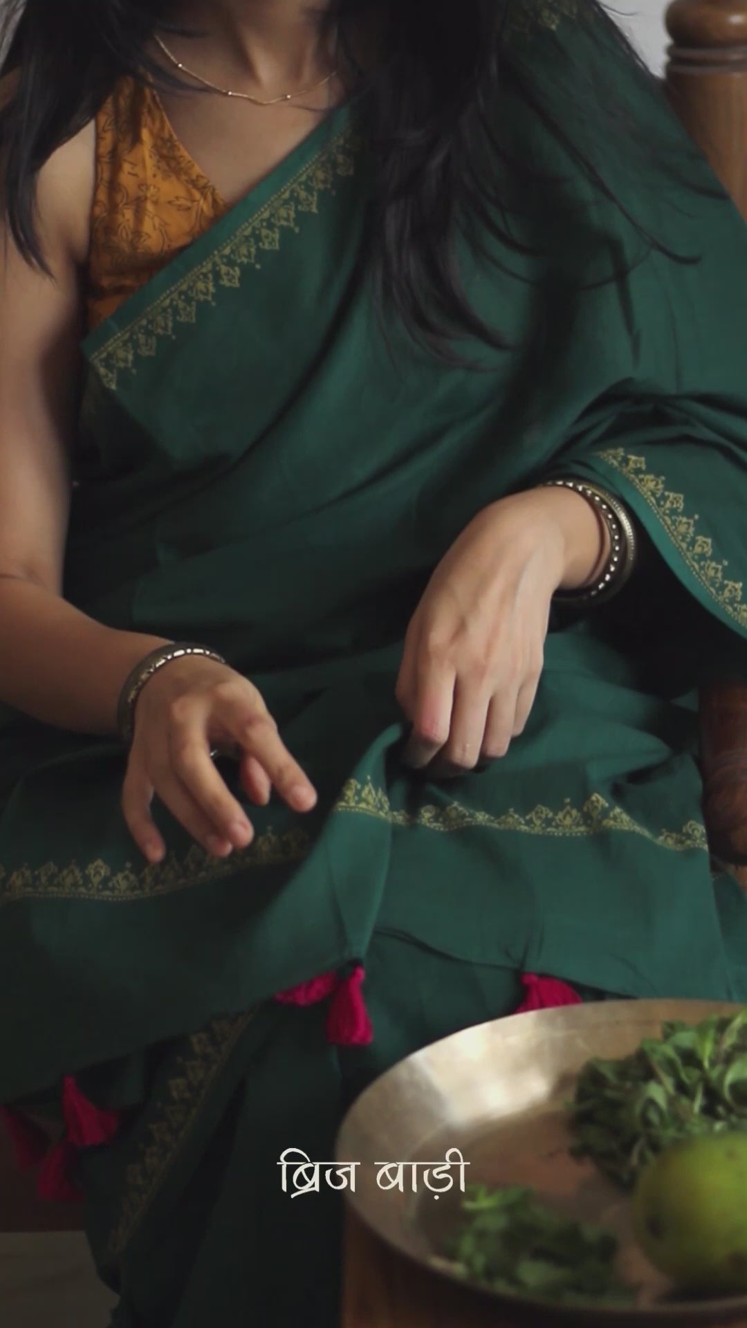 Deep green soft and light-weight cotton saree by Brij Bari, featuring a delicate hand block printed border in vibrant ochre yellow that contrasts beautifully with the rich green. The saree is finished with pink handmade thread tassels on the pallu, adding a touch of traditional charm. It comes with a free matching block printed blouse piece, completing the handcrafted look. Perfect for everyday wear, casual outings, or semi-formal occasions, with free shipping pan India.