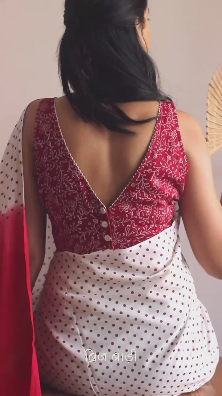 Off-white soft and light-weight cotton saree by Brij Bari, featuring deep red ombre pallu and small retro-style polka dot hand block prints. Accented with handcrafted mustard thread tassels on the pallu for a touch of artisanal charm. Includes a free matching hand block printed blouse piece. A timeless piece combining elegance, tradition, and comfort—crafted by Brij Bari’s skilled artisans.