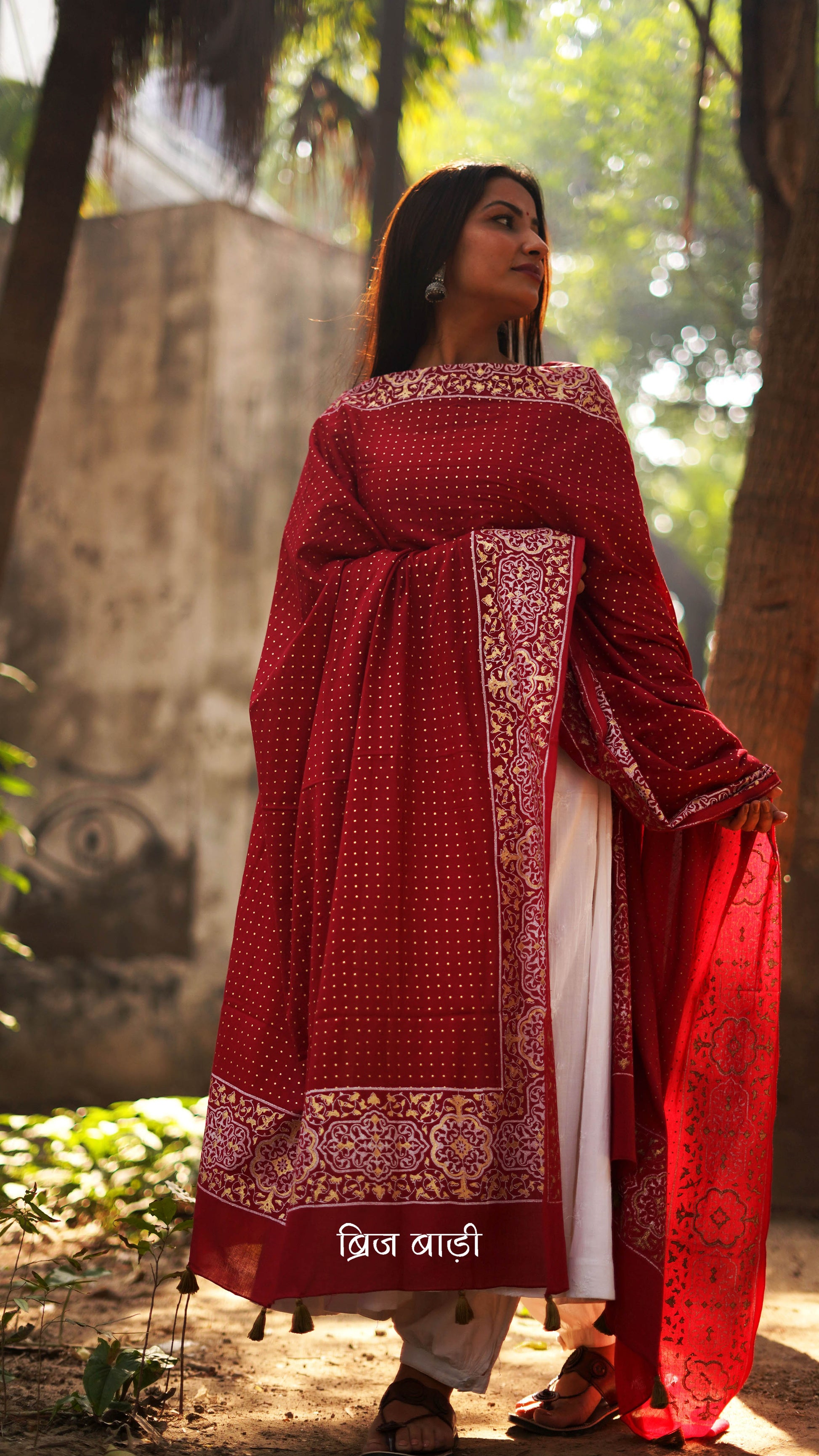 Red buttery soft and lightweight cotton dupatta by Brij Bari, hand block printed with a beautiful golden and ivory pattern that adds a festive yet refined touch. Accented with handmade olive green thread tassels on both ends of the pallu, this dupatta is crafted for comfort and elegance. A versatile piece to pair effortlessly with daily or festive suits. Free shipping pan India.
