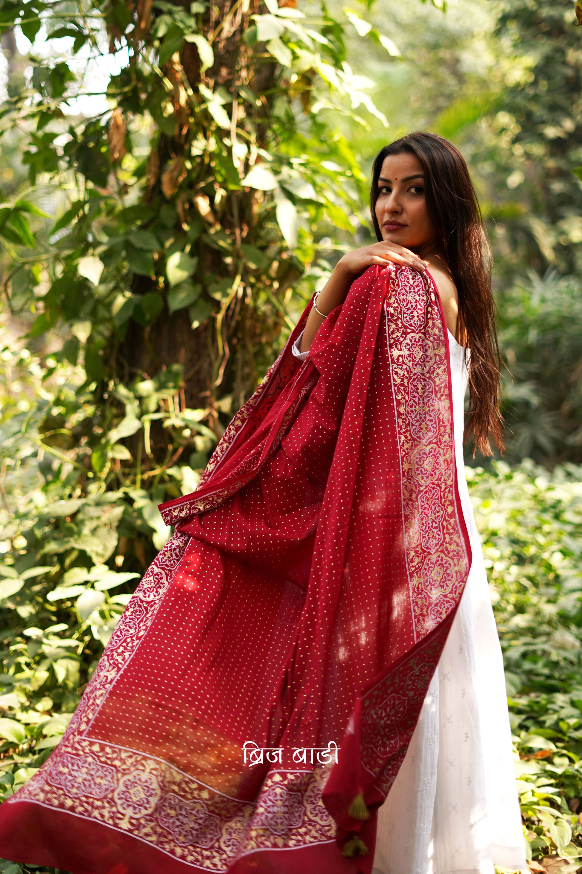 Red buttery soft and lightweight cotton dupatta by Brij Bari, hand block printed with a beautiful golden and ivory pattern that adds a festive yet refined touch. Accented with handmade olive green thread tassels on both ends of the pallu, this dupatta is crafted for comfort and elegance. A versatile piece to pair effortlessly with daily or festive suits. Free shipping pan India.