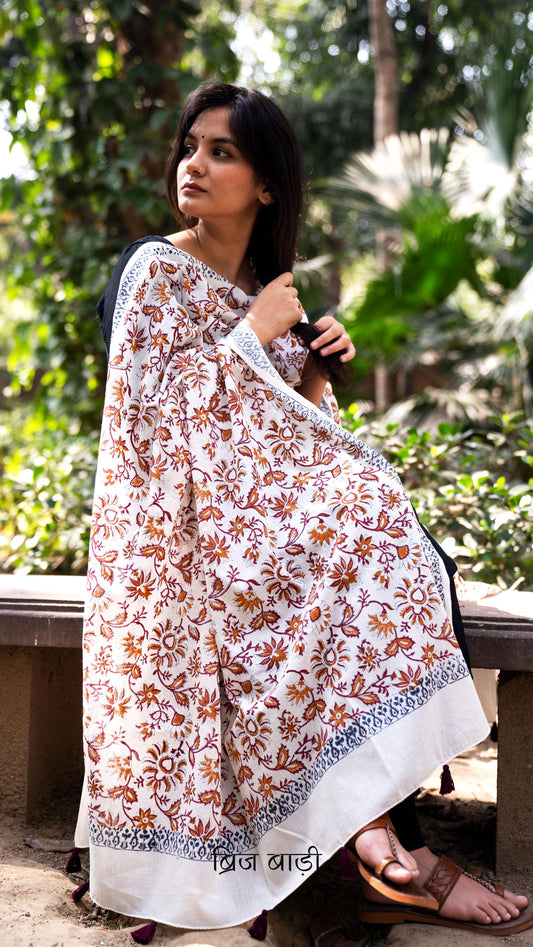 Off white soft and lightweight cotton dupatta by Brij Bari, hand block printed with a vibrant multicolour floral pattern. Finished with handmade purple thread tassels on both ends of the pallu, this artisanal dupatta adds a lively pop of colour to your daily suits while offering all-day breathable comfort. Ideal for versatile styling. Free shipping pan India.
