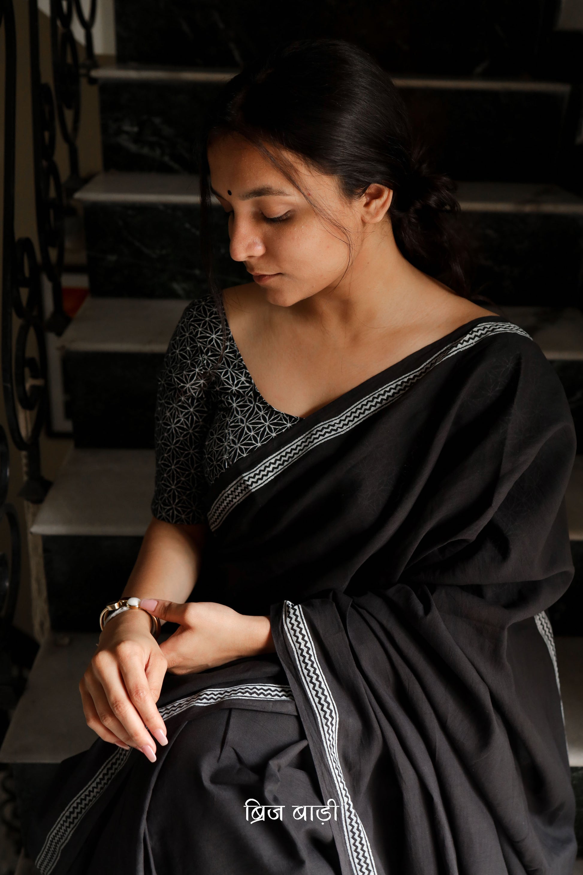 Black soft and light-weight cotton saree by Brij Bari with a simple and elegant hand block printed border in white for a timeless minimal look. Made from breathable, easy-to-drape cotton, this saree is perfect for everyday wear, offering effortless style & comfort. Pallu is finished with handmade mustard thread tassels, adding a handcrafted detail and a pop of colour. Includes a free hand block printed blouse piece designed to complement the sar the saree’s clean, classic border design. 