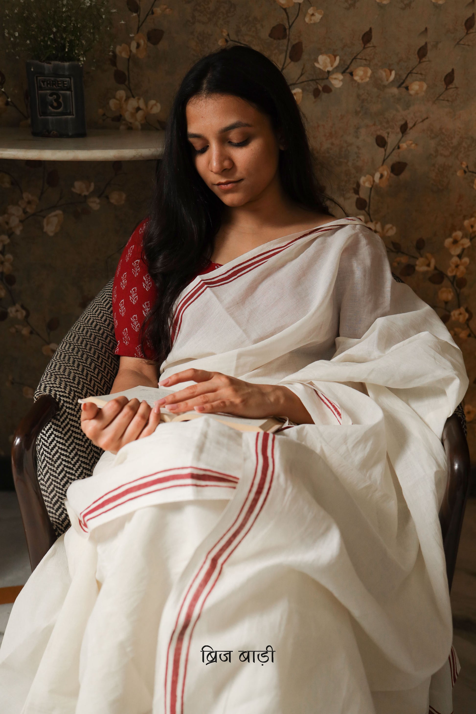 Off-white soft and light-weight cotton saree by Brij Bari with a simple and elegant hand block printed stripe pattern border in rich red. Designed for breathable comfort and effortless everyday style, this saree drapes beautifully for work, casual days or relaxed occasions. The pallu is finished with delicate light green handmade thread tassels adding a subtle artisanal detail. It comes with a free hand block printed blouse piece thoughtfully designed to complement the saree’s minimal design. Free Shipping 
