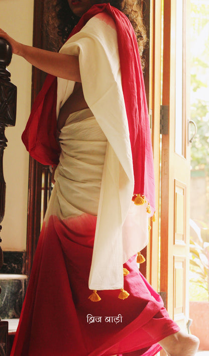 Red ombré soft cotton saree by Brij Bari, crafted for effortless elegance and all-day comfort. The subtle blend of tones adds fluidity and grace to the drape, making it perfect for both everyday wear and special occasions. The pallu is adorned with handcrafted mustard thread tassels, lending a warm, artisanal touch. It comes with a free hand block printed blouse piece that complements the saree’s minimal yet striking aesthetic. Available in 8 beautiful colour options, this saree is a timeless choice