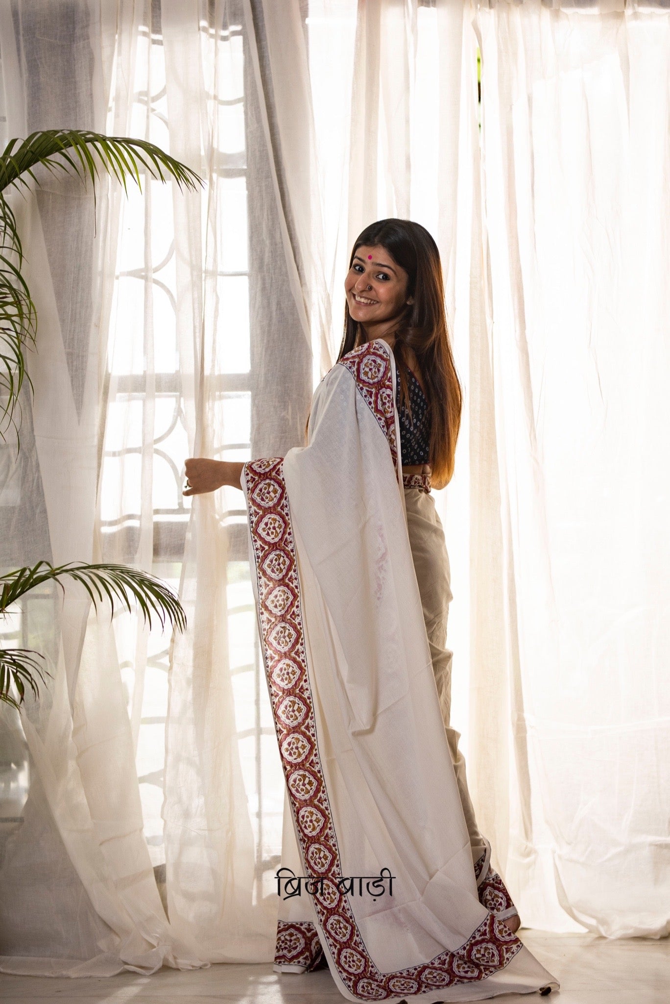 Off white soft and light-weight cotton saree by Brij Bari, featuring a delicate and intricate multicolour hand block printed border crafted by skilled artisans. Designed for all-day comfort and effortless style, this saree is detailed with olive green handmade thread tassels on the pallu. It comes with a free block printed blouse piece, making it a versatile pick for everyday wear, casual gatherings, and relaxed festive occasions. Free shipping pan India.