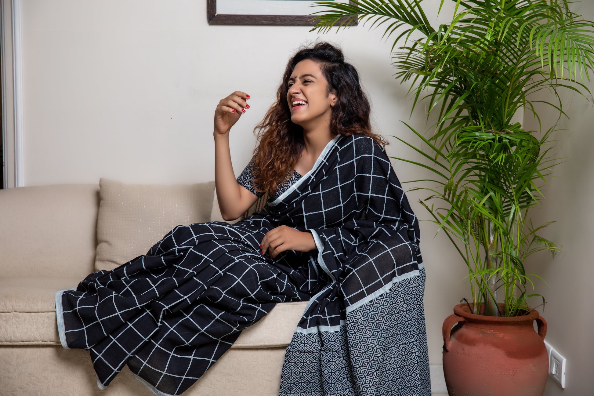 Black soft and light-weight cotton saree by Brij Bari, hand block printed in white with a classic check pattern on the body and a striking geometrical pattern on the pallu. Detailed with pink handmade thread tassels that add a charming, handcrafted touch. This saree comes with a free matching block printed blouse piece, offering a complete, artisanal look. A versatile, breathable saree perfect for everyday wear, casual outings, or semi-formal occasions, with free shipping pan India. Available in 2 colours
