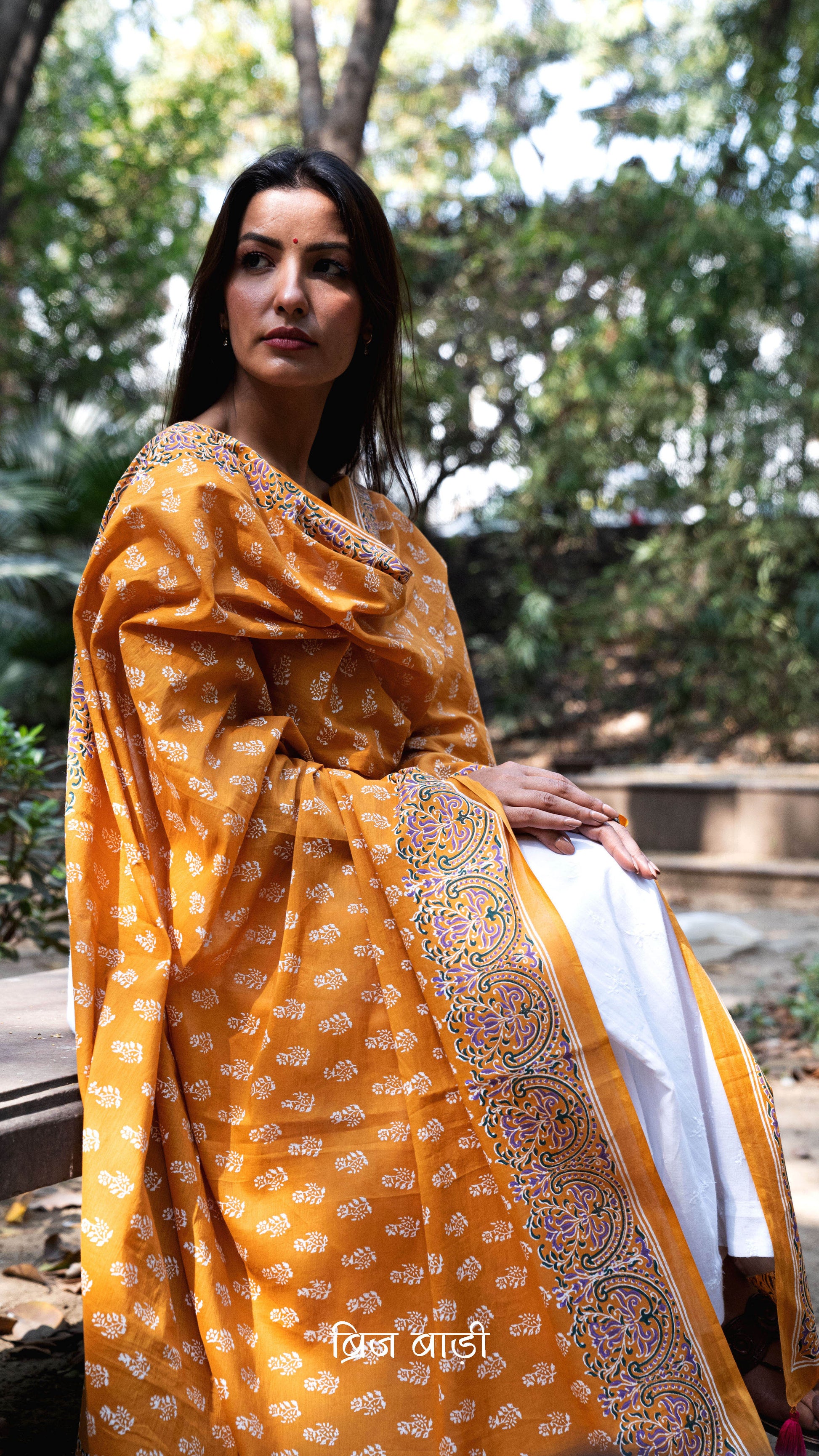 Ochre yellow soft and lightweight cotton dupatta by Brij Bari, hand block printed with a charming floral motif pattern for an artisanal touch. Accented with pink handmade thread tassels on both ends of the pallu, this versatile dupatta adds a vibrant pop to your daily suits, offering breathable comfort and effortless style for all-day wear. Free shipping pan India.
