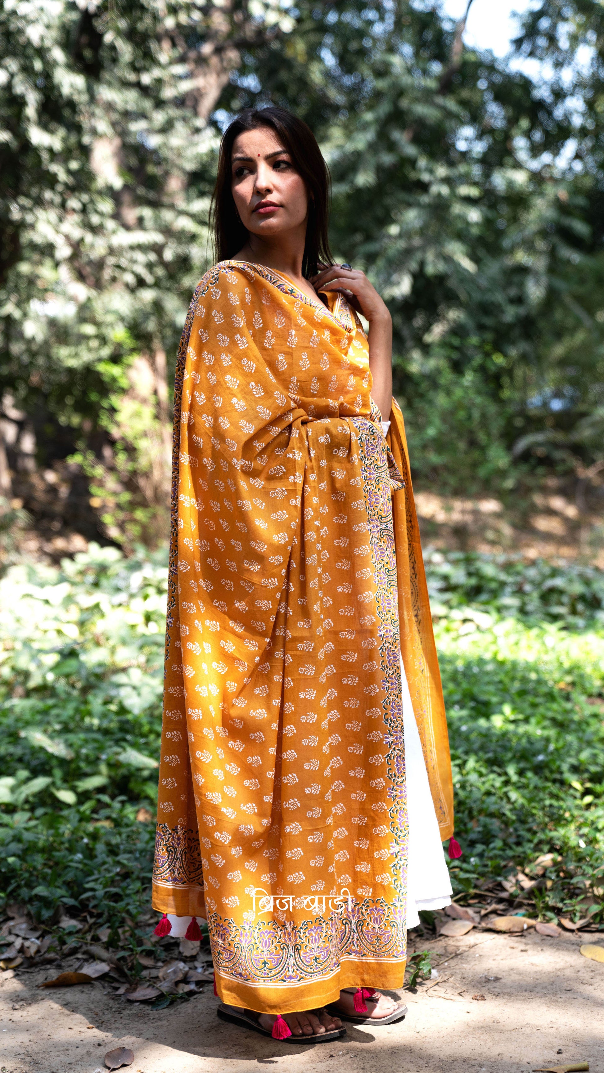 Ochre yellow soft and lightweight cotton dupatta by Brij Bari, hand block printed with a charming floral motif pattern for an artisanal touch. Accented with pink handmade thread tassels on both ends of the pallu, this versatile dupatta adds a vibrant pop to your daily suits, offering breathable comfort and effortless style for all-day wear. Free shipping pan India.