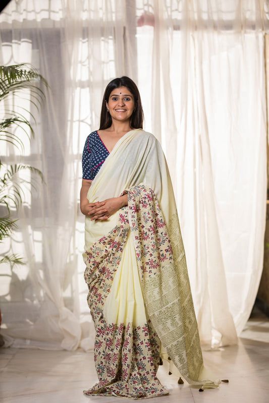 Pastel yellow buttery soft and light-weight cotton saree by Brij Bari, featuring a delicate and intricate multicolour floral hand block print on the skirt, complemented by an olive green floral pattern on the pallu. Detailed with olive green handmade thread tassels on the pallu, this saree comes with a free matching block printed blouse piece. Designed for all-day comfort, effortless elegance, and versatile styling. Free shipping available pan India.